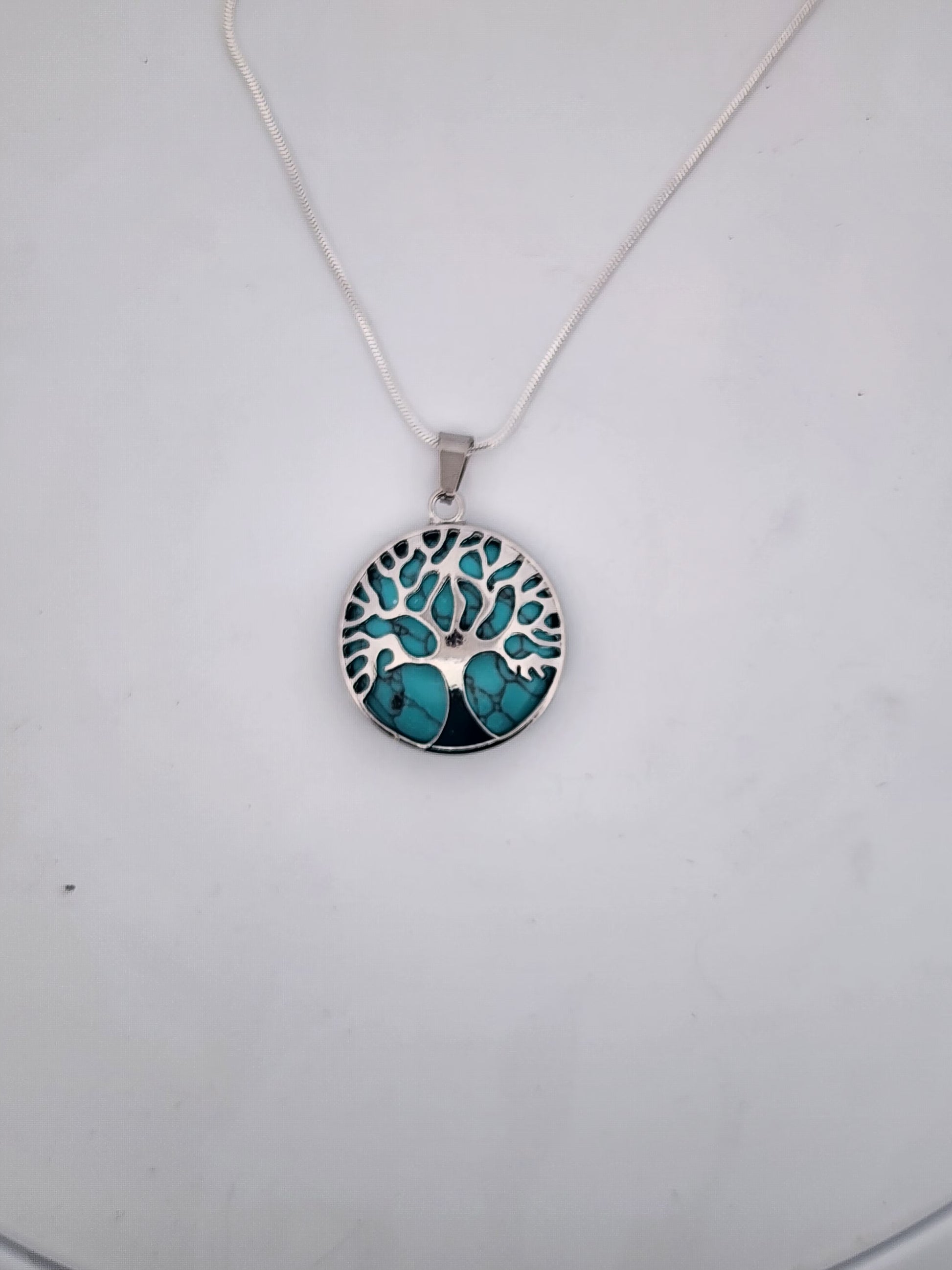 Necklace with a tree of life pendant featuring turquoise stones on a white background
