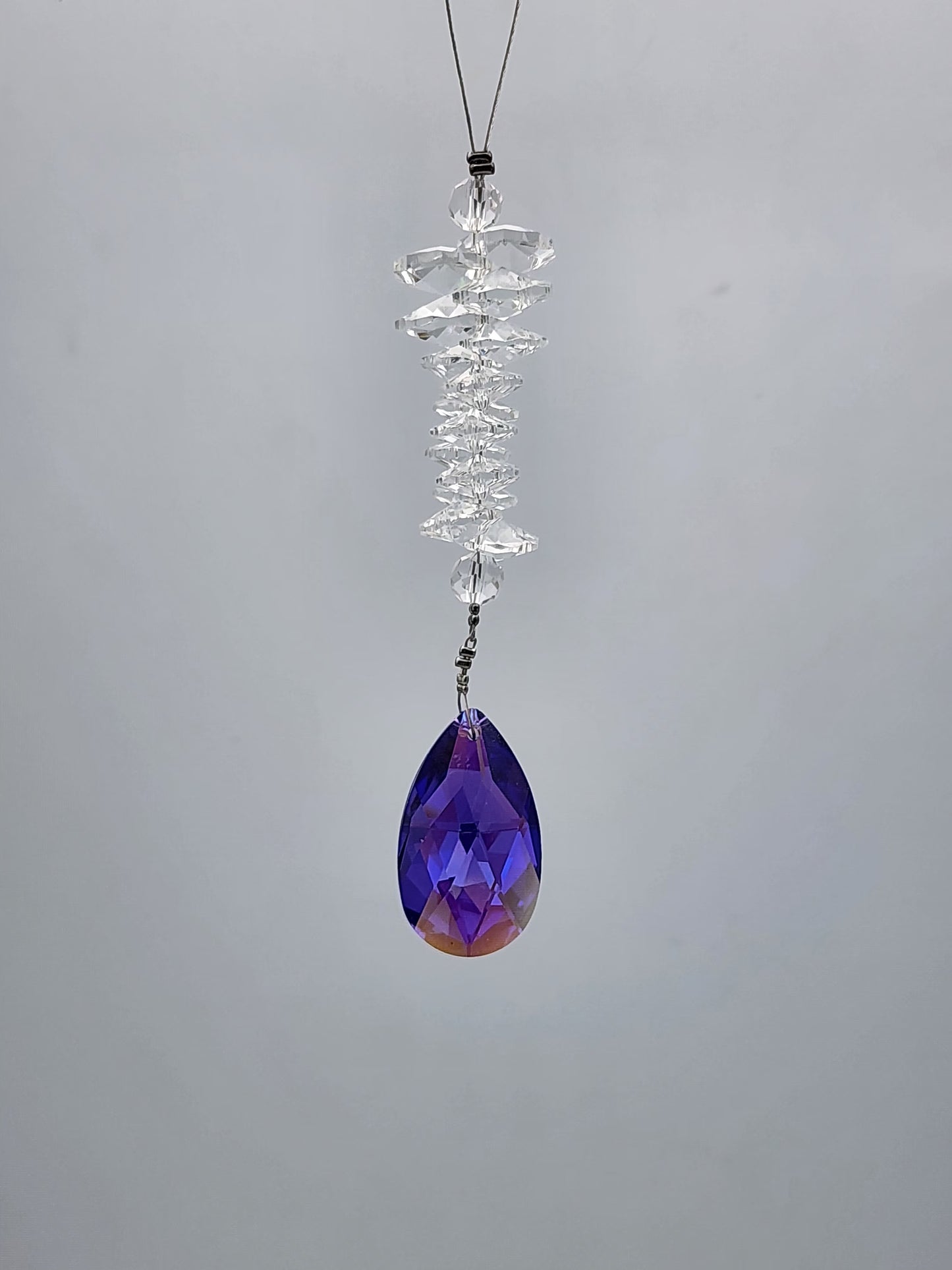 Crystal hanging ornament with a purple teardrop on a gray background