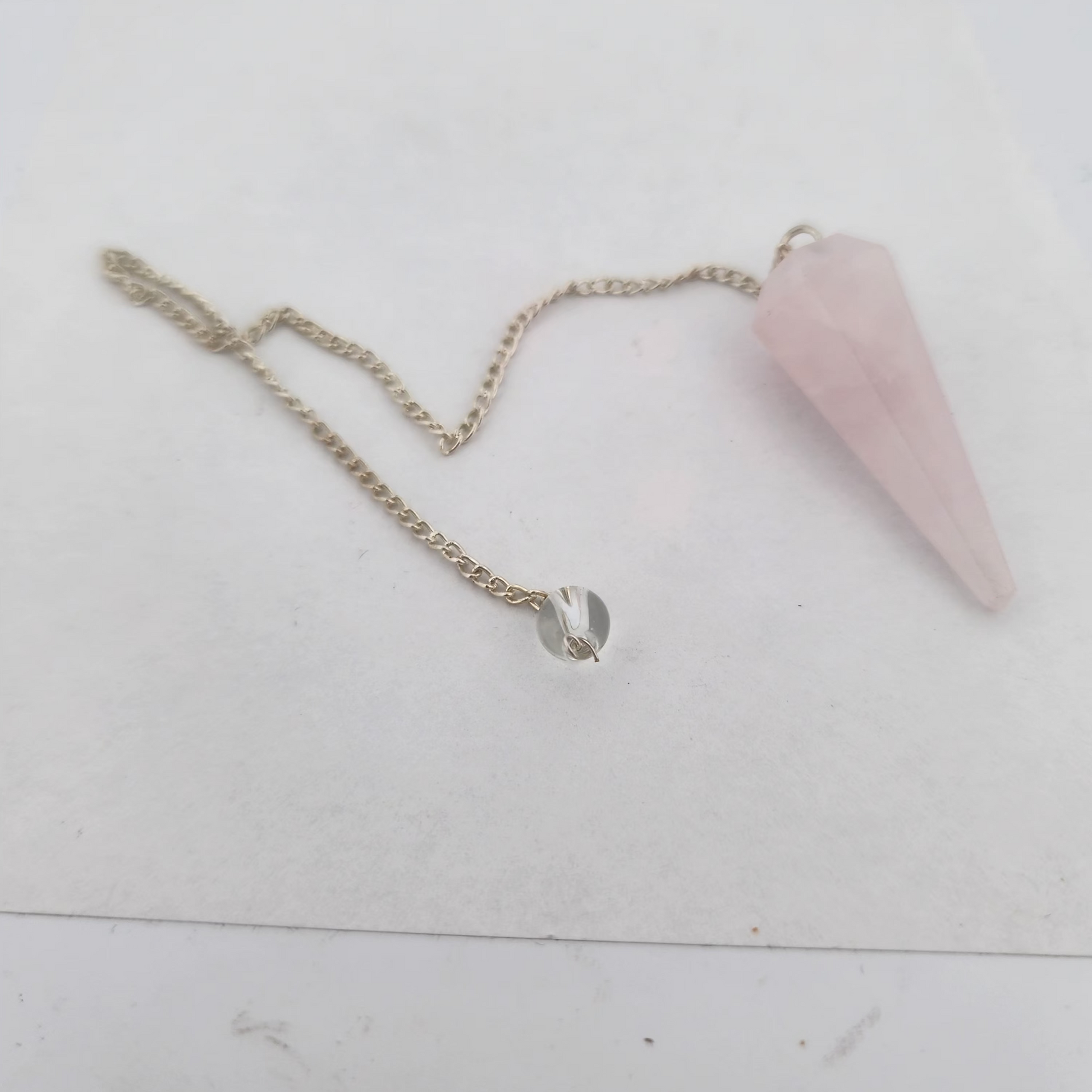 Pink crystal pendulum on a white surface