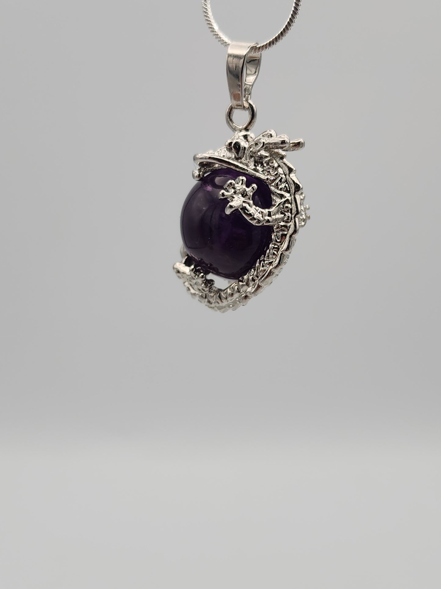 Silver pendant with a purple gemstone on a gray background