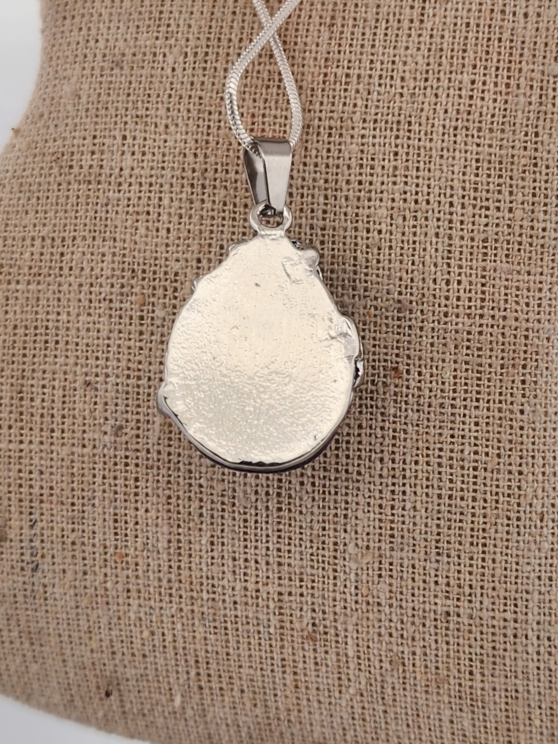 Silver pendant on a beige fabric background