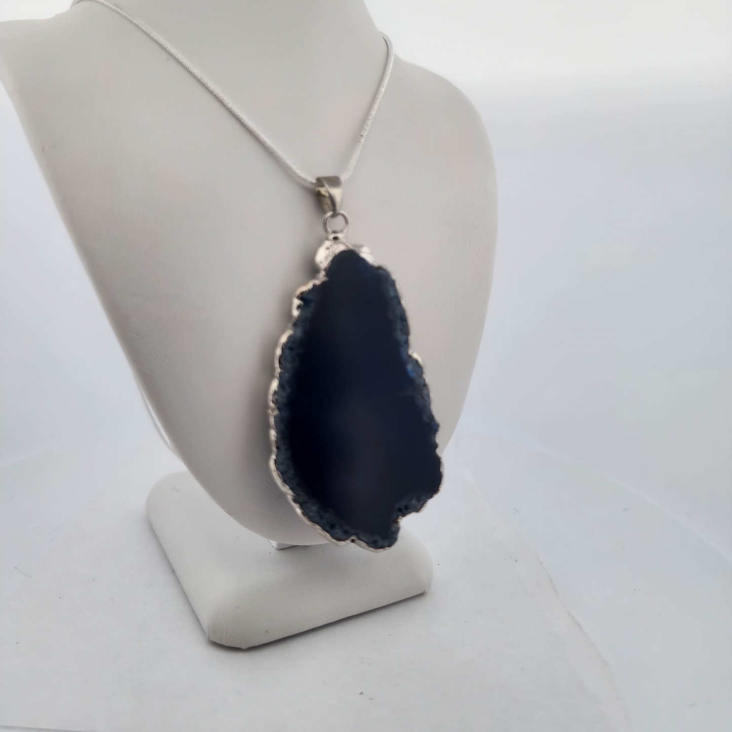 Navy blue pendant on a white mannequin bust with a white background