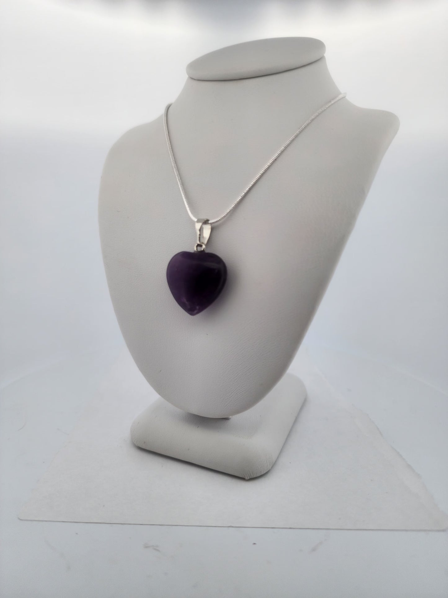 Necklace with a purple heart pendant on a gray mannequin bust against a white background