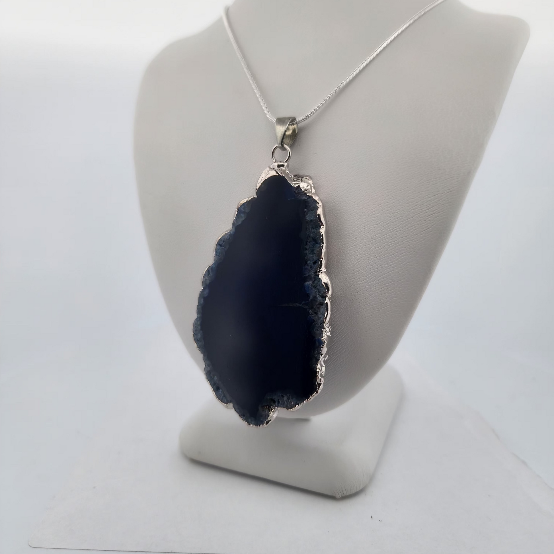 Navy blue geode pendant on a gray mannequin bust against a white background