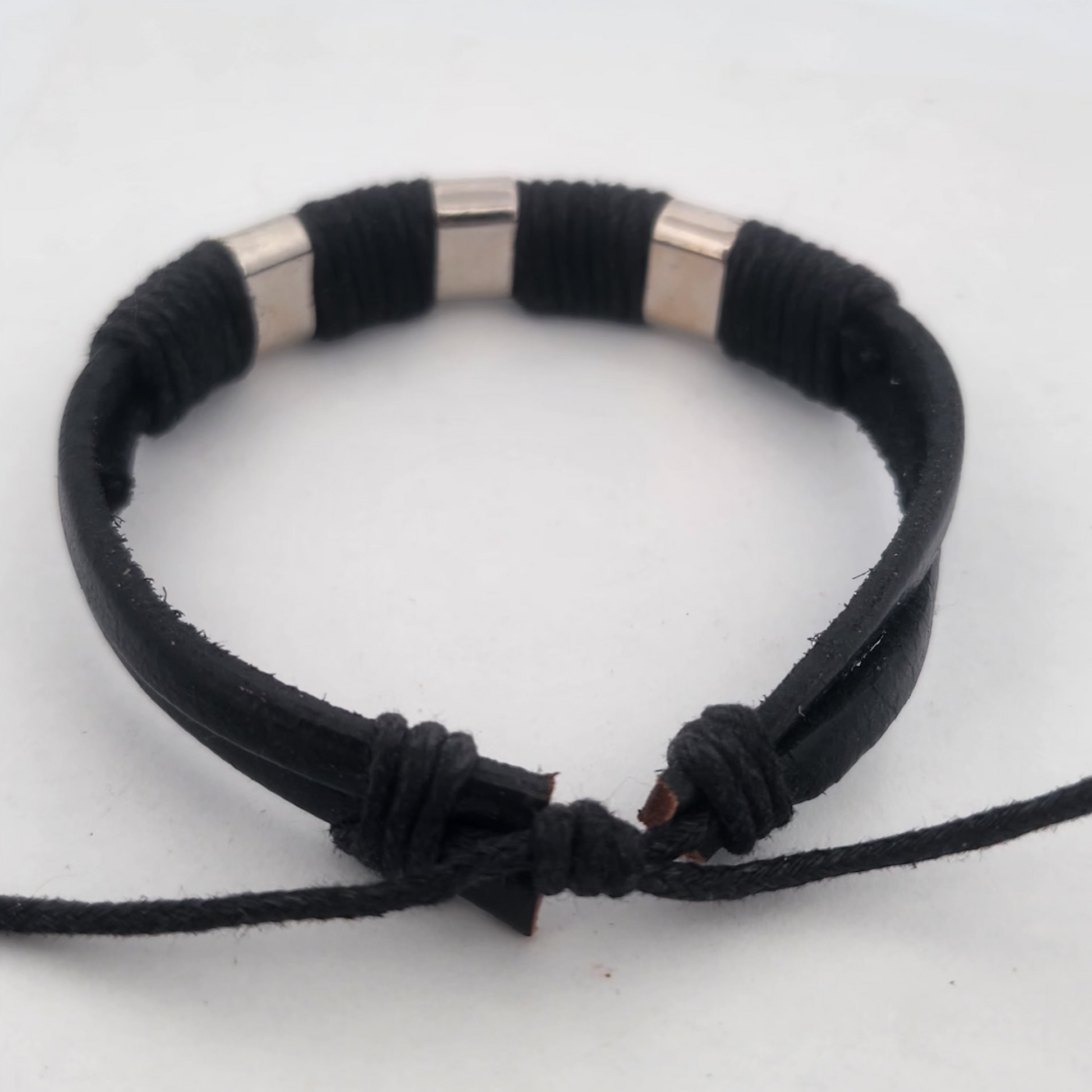 Black braided bracelet with silver cylindrical beads on a white background