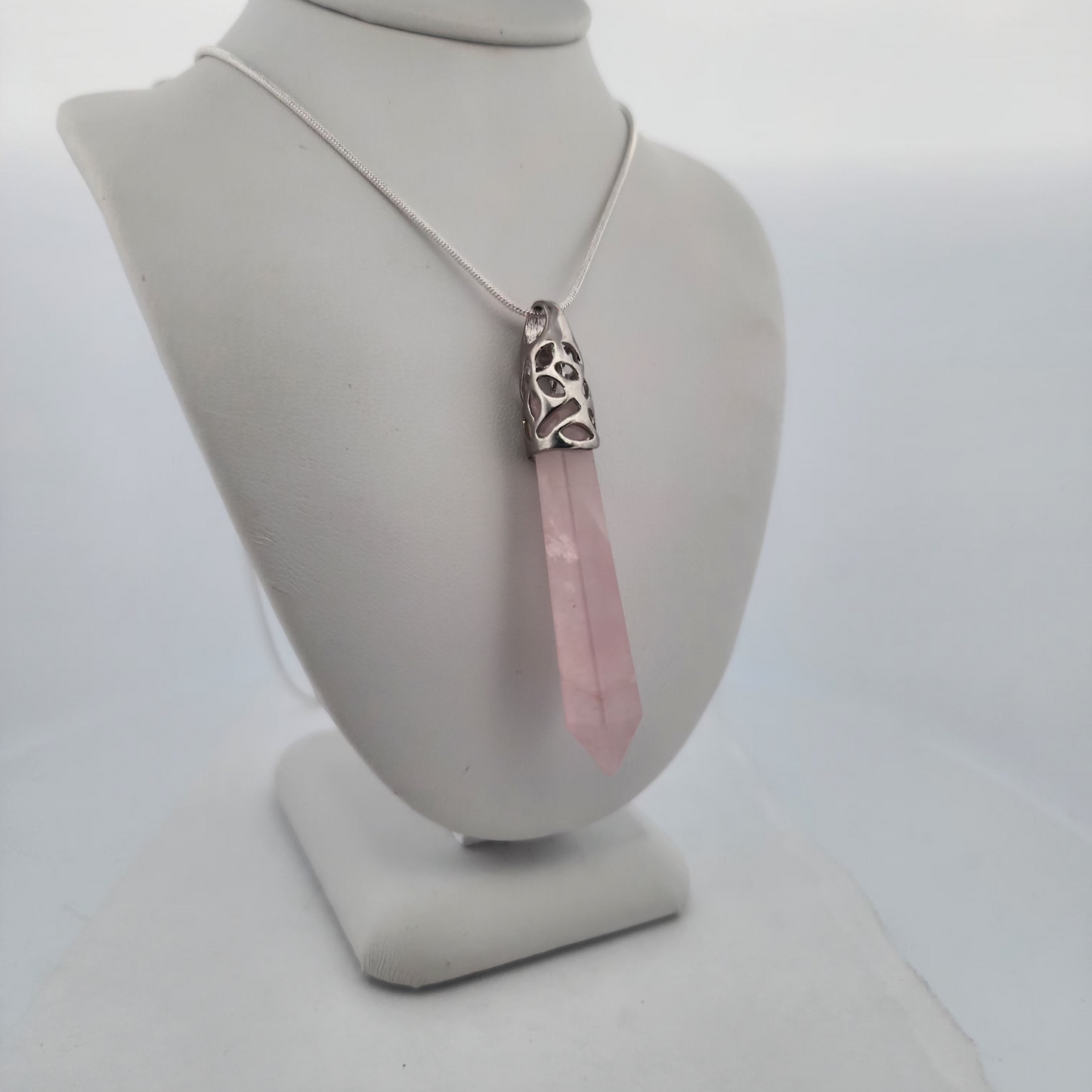 Necklace with a pink pendant on a mannequin bust against a white background