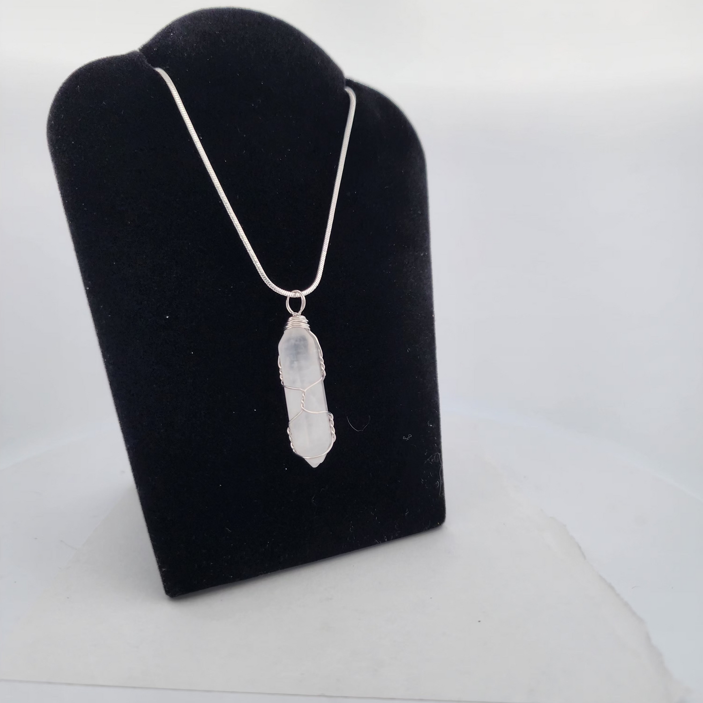 Necklace with a pendant on a black jewelry stand against a white background