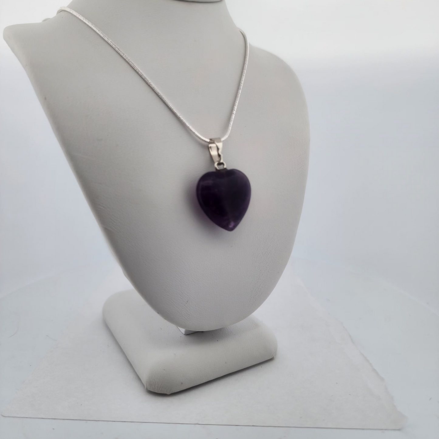 Necklace with a purple heart pendant on a gray mannequin bust against a white background