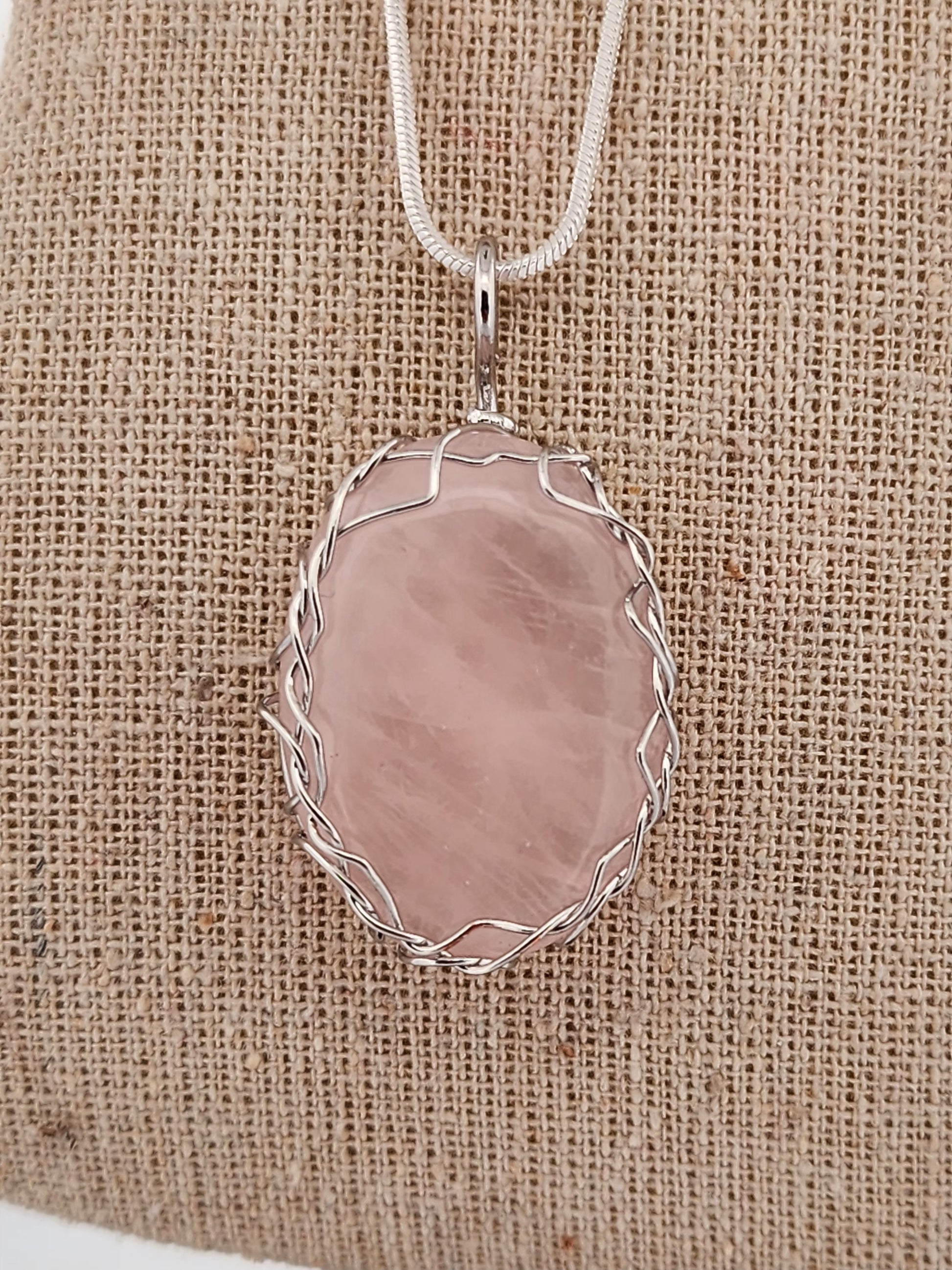 Necklace with a pink pendant on a burlap background