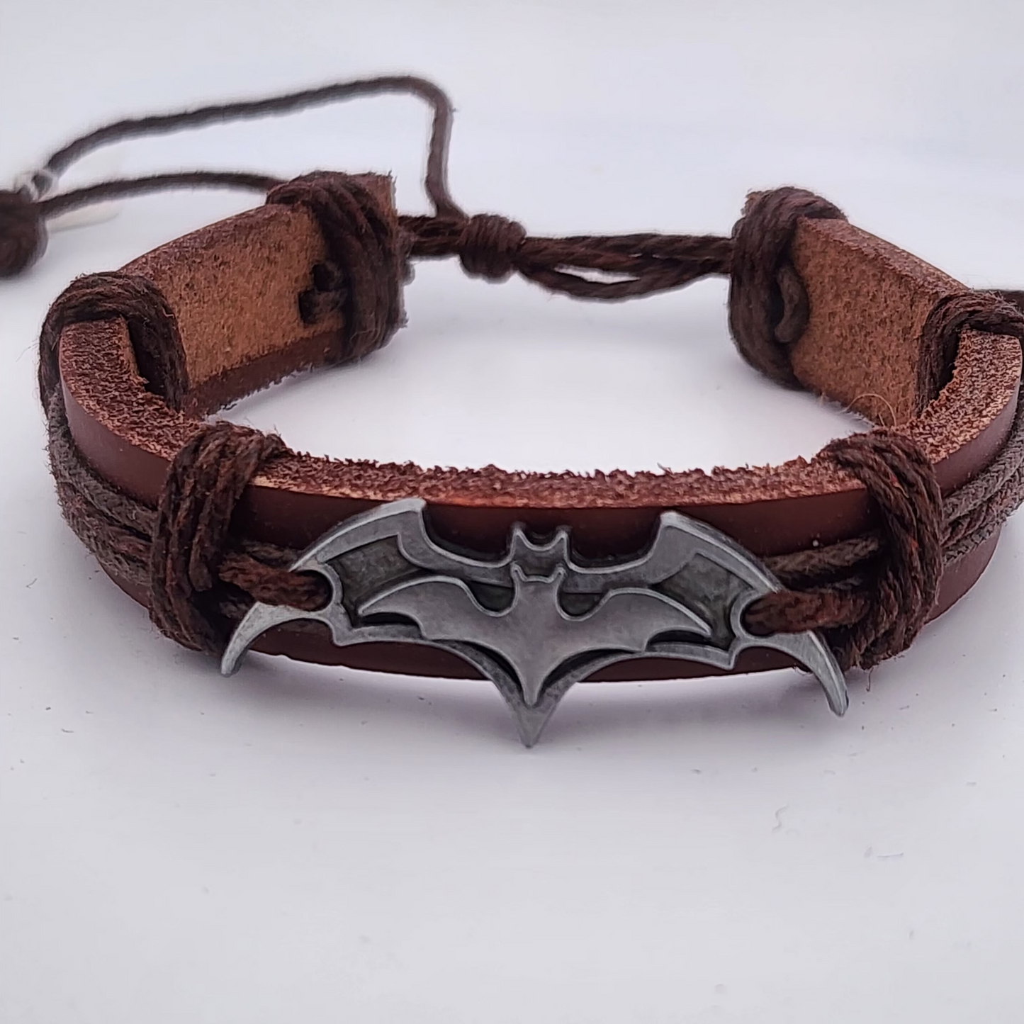 Brown leather bracelet with a silver bat-shaped clasp on a white background