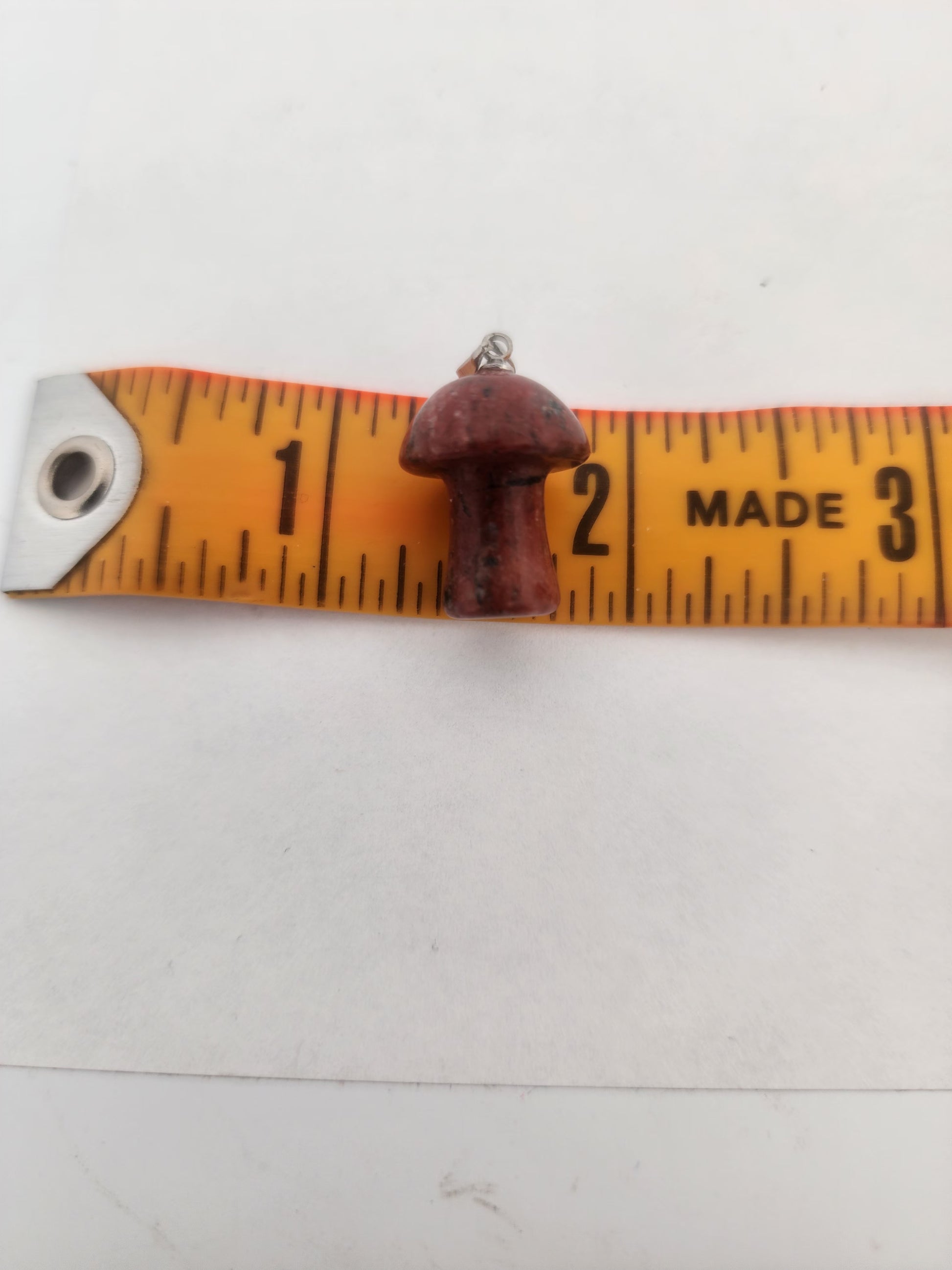 Small mushroom-shaped object on a measuring tape against a white background