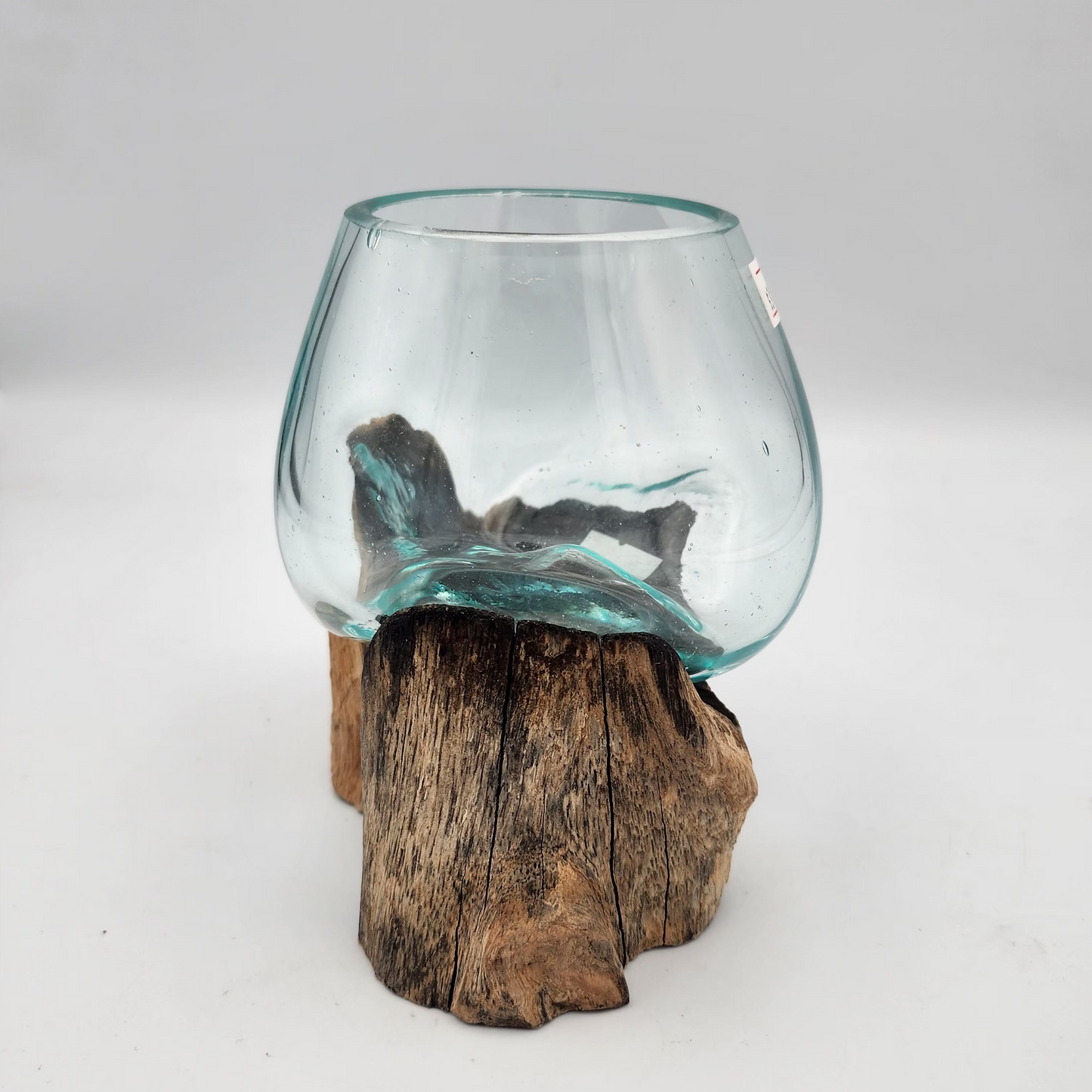 Clear glass candle holder on a wooden stump against a white background