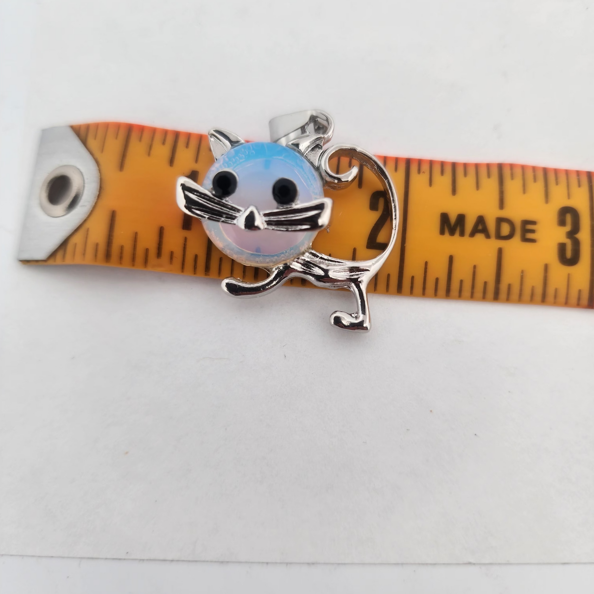 Metallic cat-shaped charm on a measuring tape against a white background