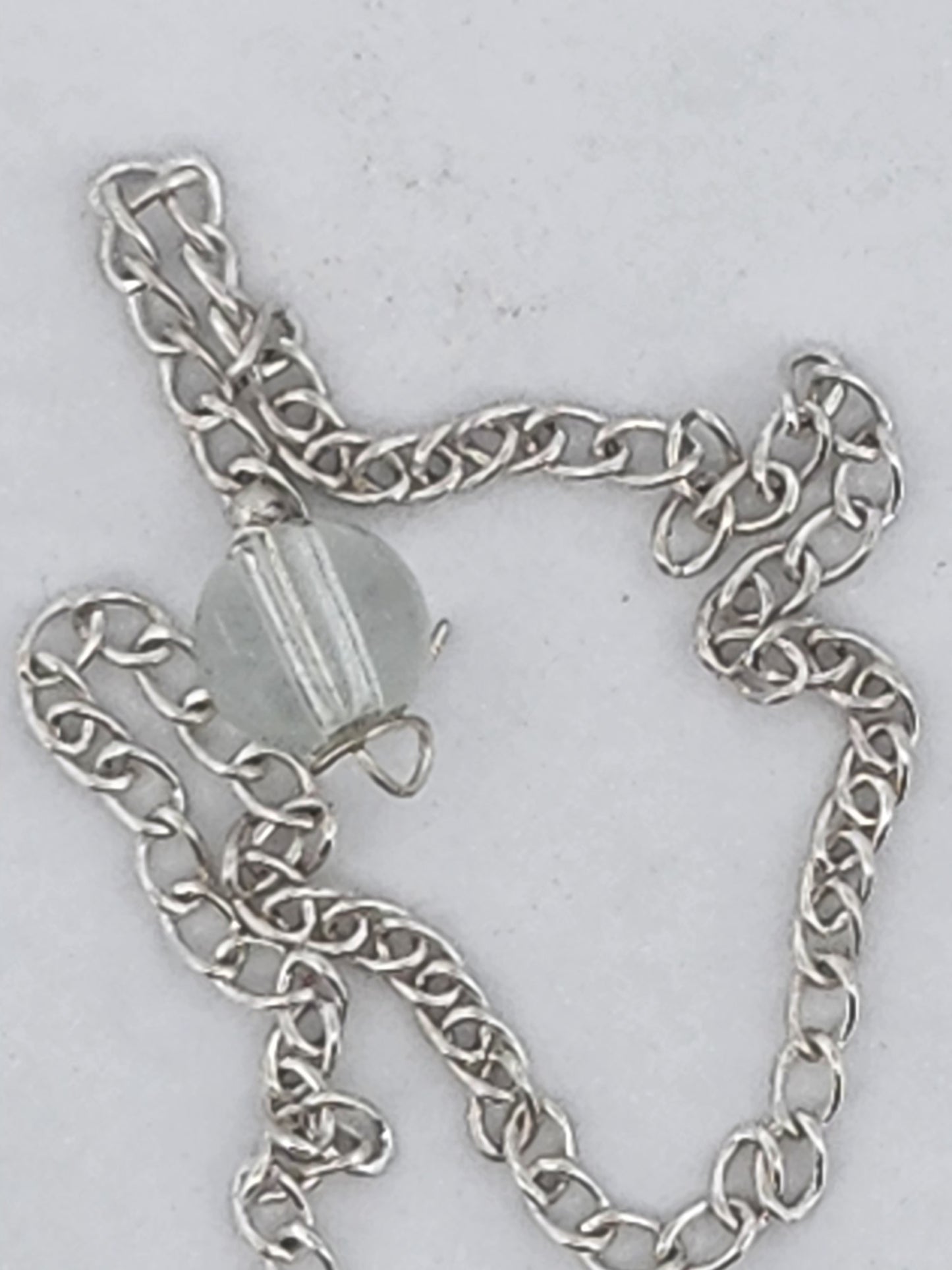 Silver chain with a clear bead on a light gray background