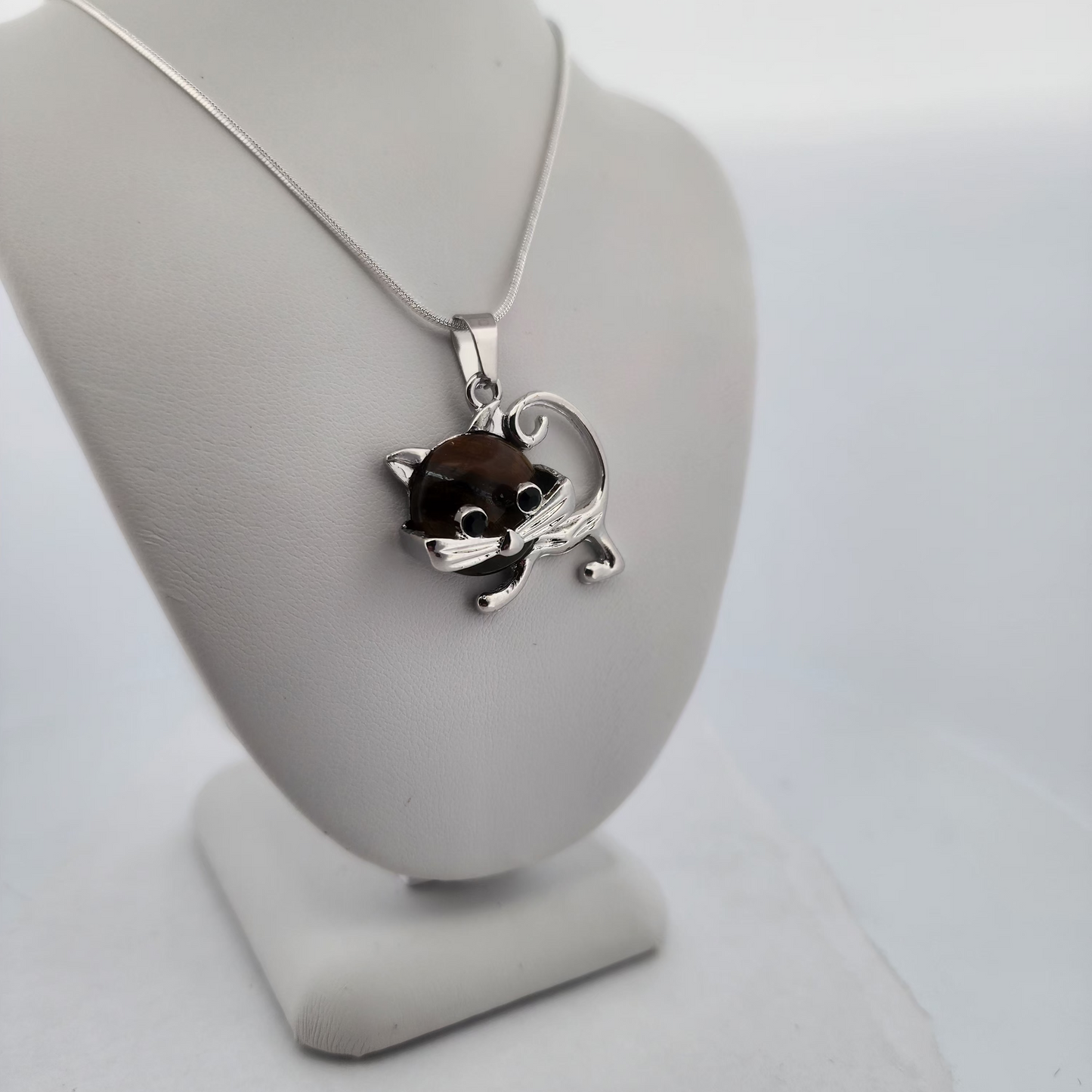 Silver necklace with a cat pendant on a white stand against a white background
