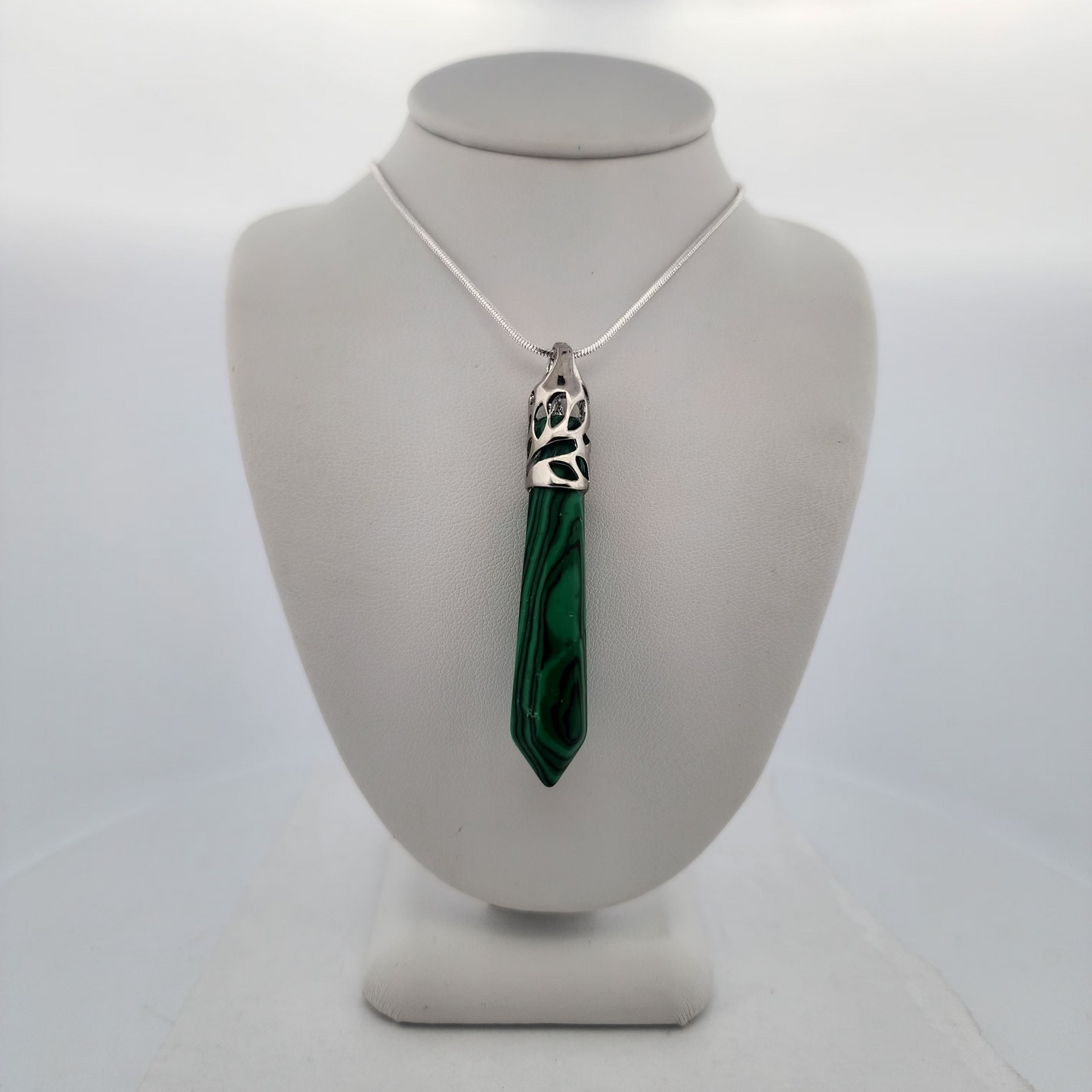 Necklace with a green pendant on a mannequin bust against a white background