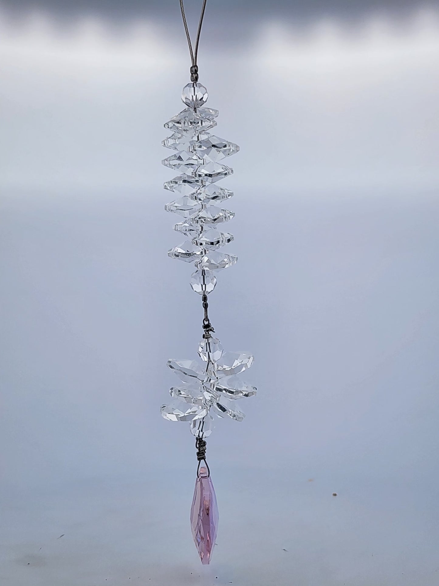 Crystal hanging ornament with a pink accent on a plain background