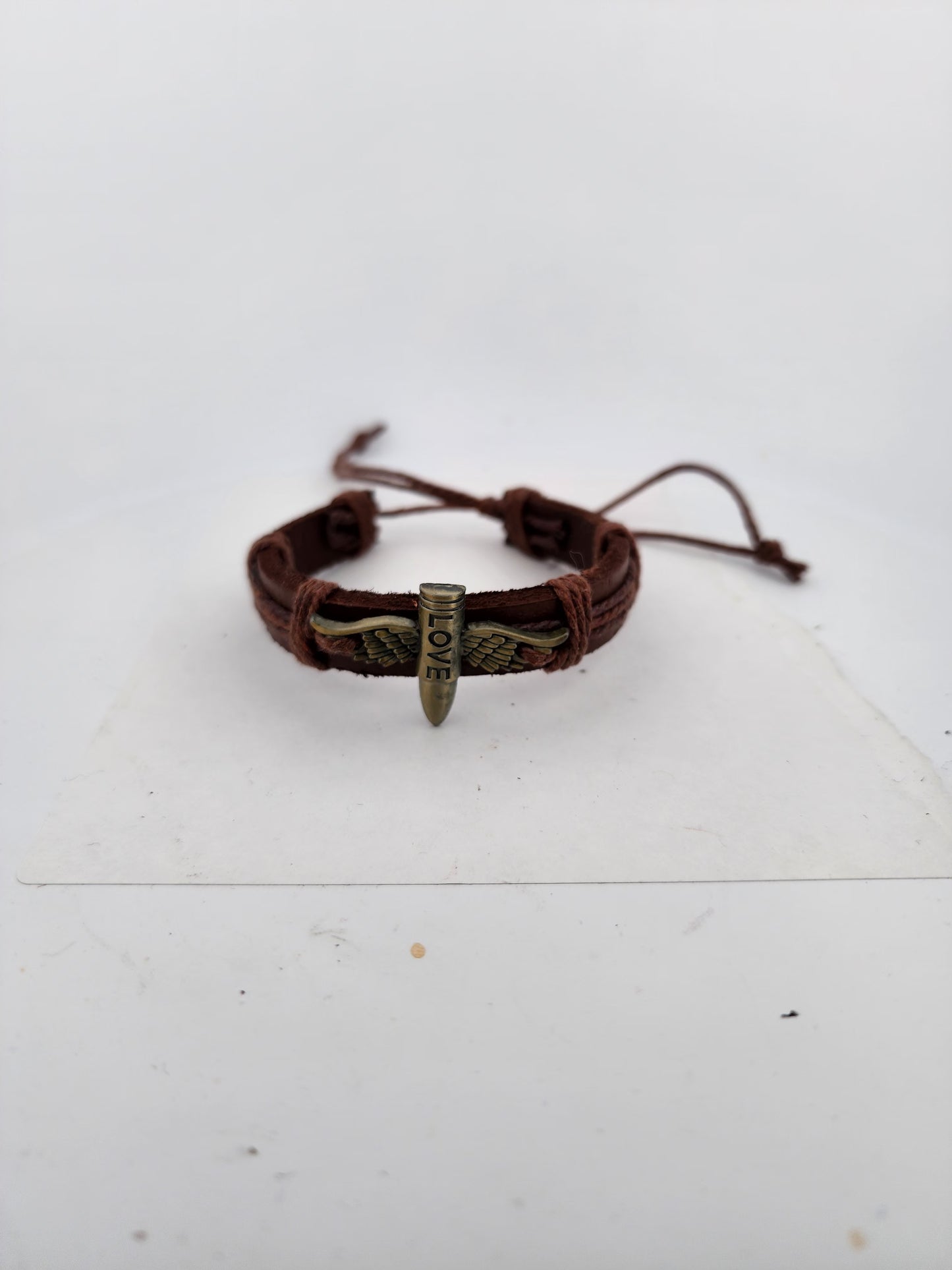 Brown leather bracelet with metal charm on a white surface