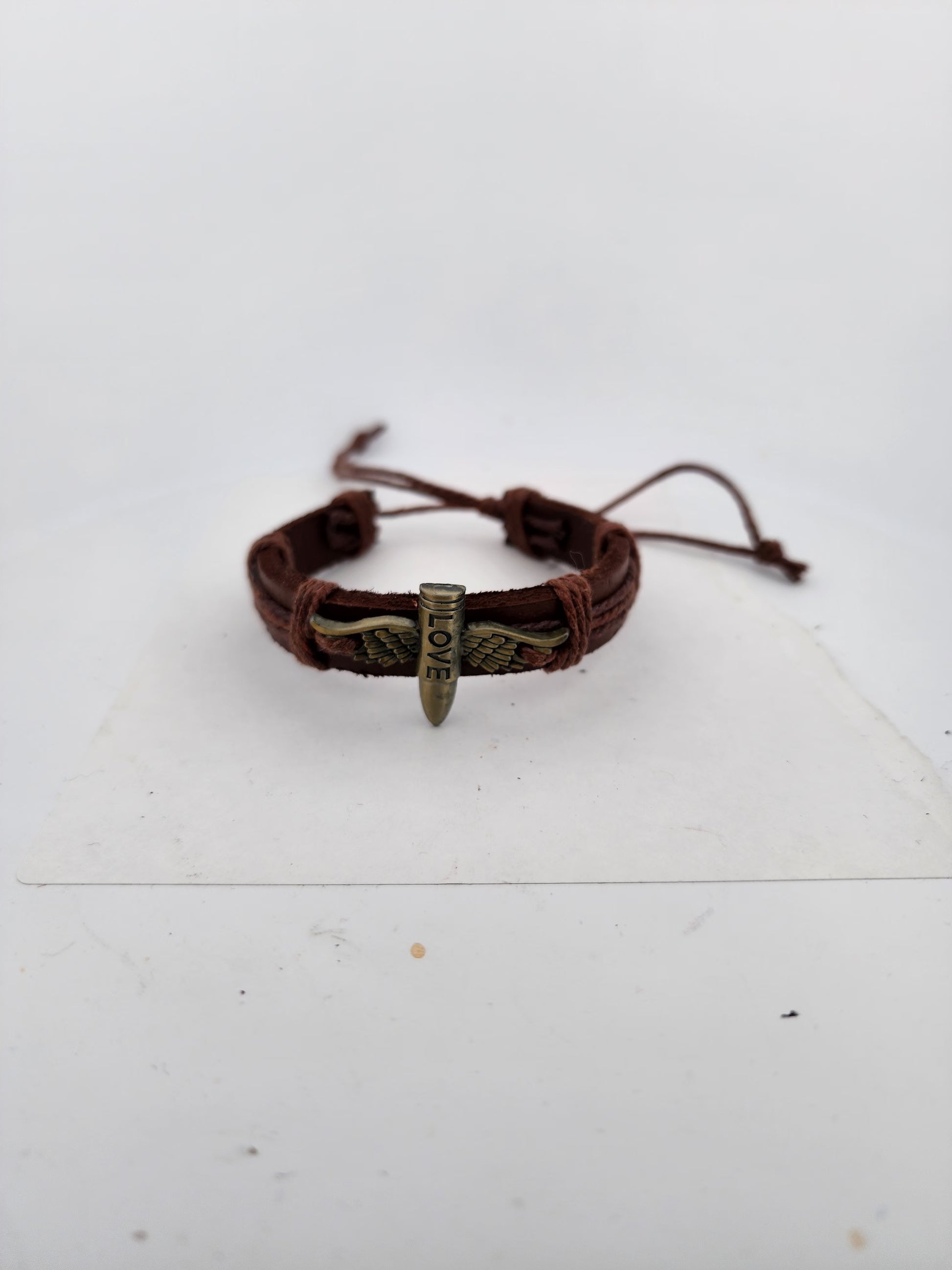 Brown leather bracelet with metal charm on a white surface