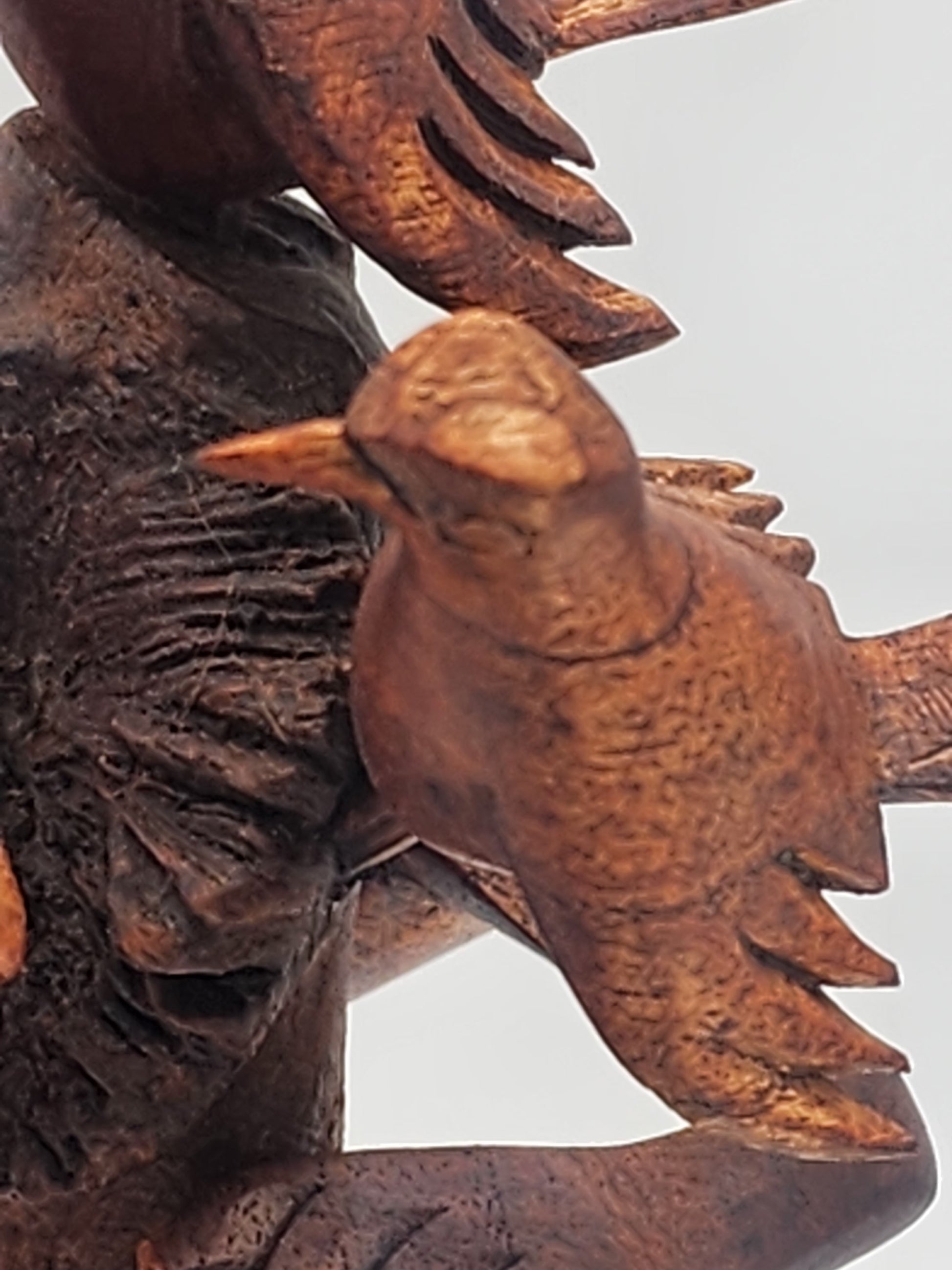 Wooden sculpture of a bird perched on a branch with a white background