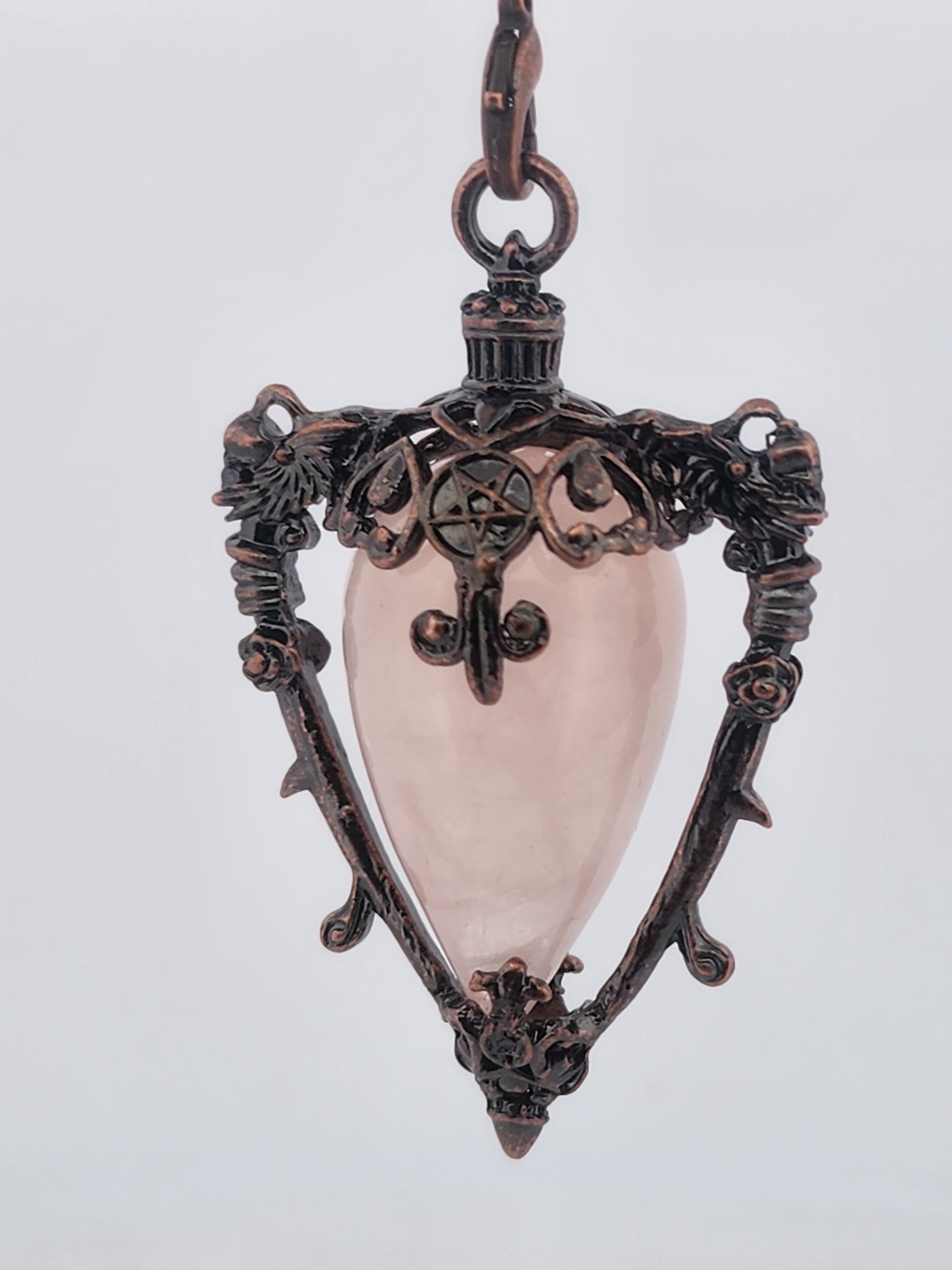 Decorative pendant with a pink central stone on a light gray background