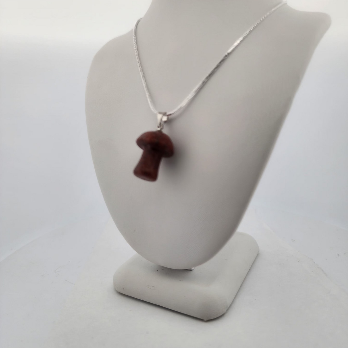 Necklace with a brown pendant on a gray mannequin bust against a white background