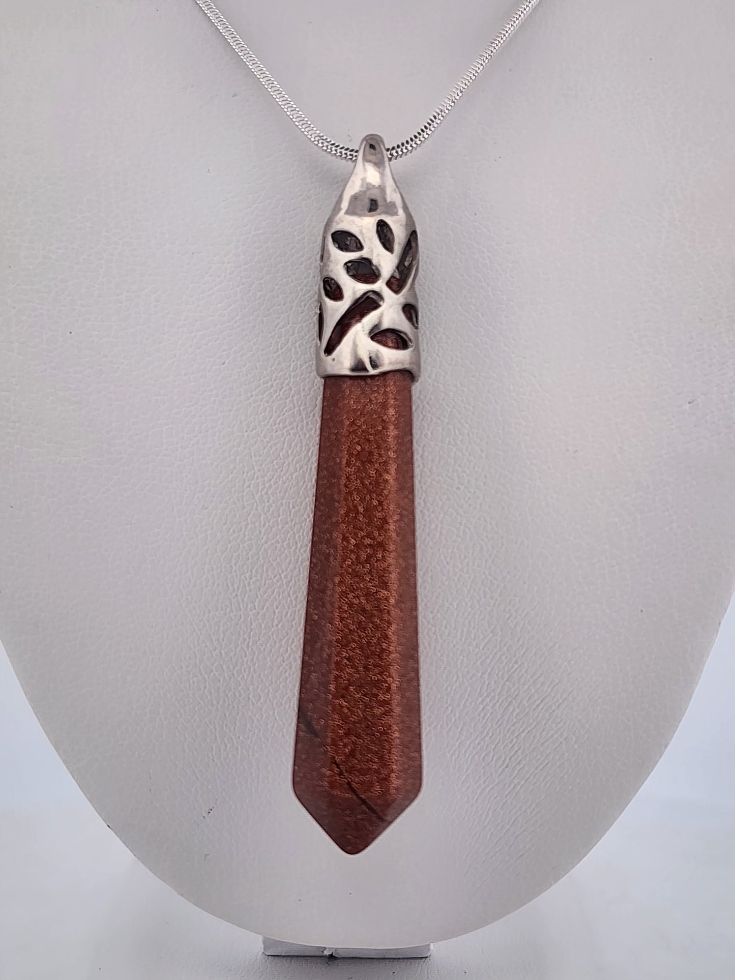 Wooden pendant with silver top on a white stand