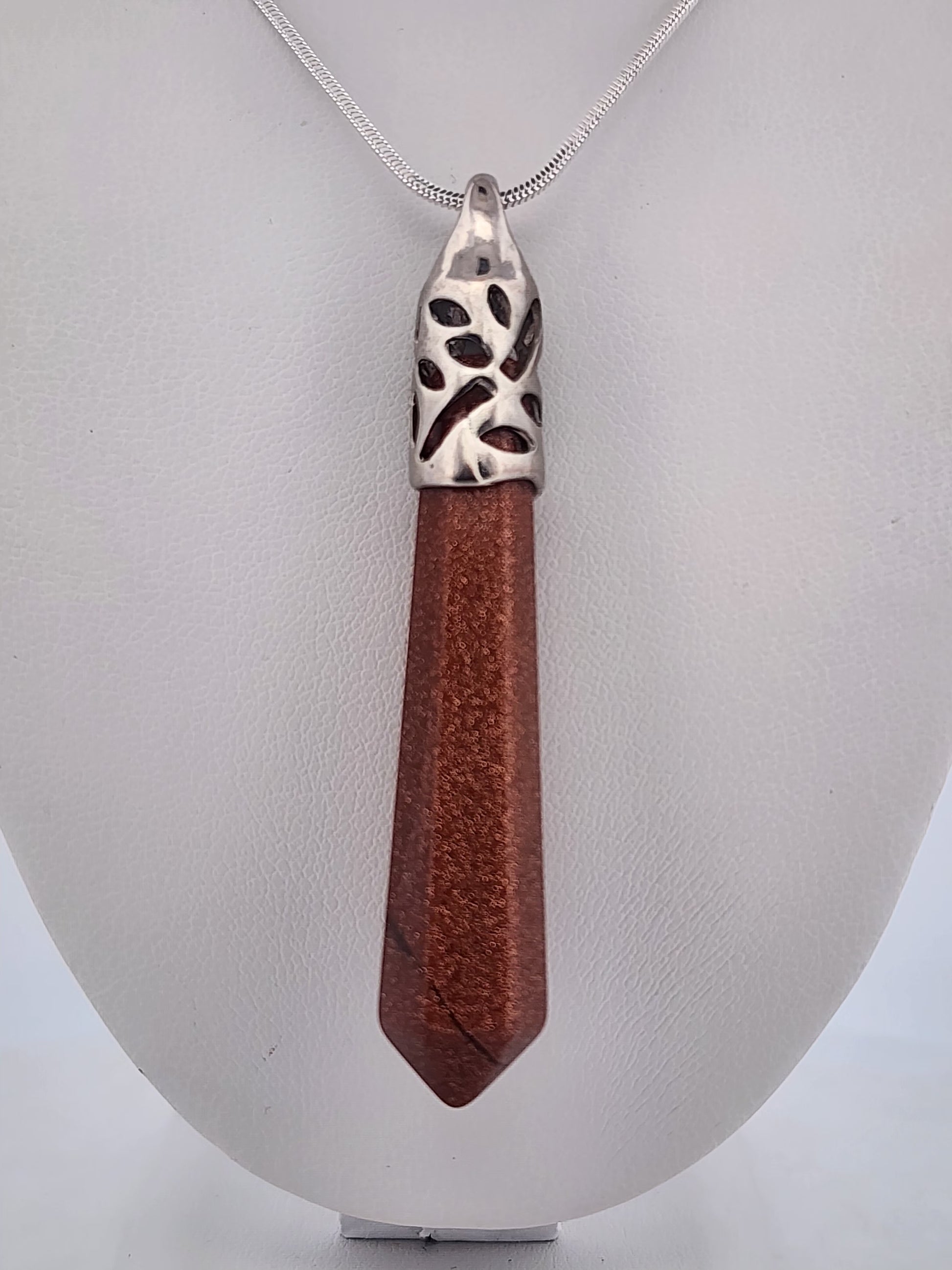 Wooden pendant with silver top on a white stand