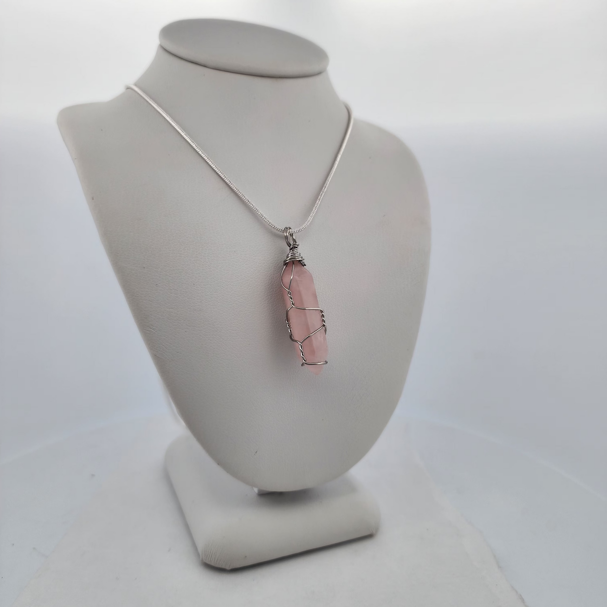 Necklace with a pink pendant on a white mannequin bust against a white background