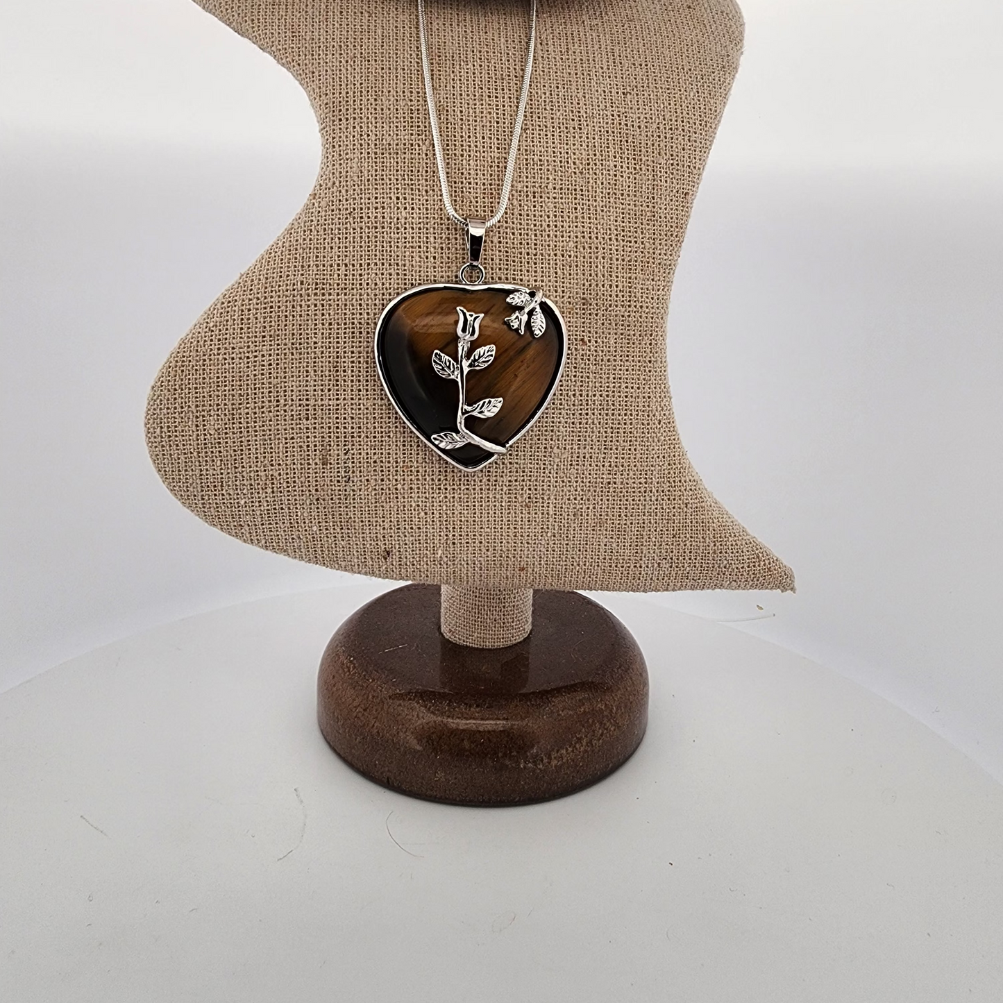 Heart-shaped pendant necklace on a mannequin bust with a plain background