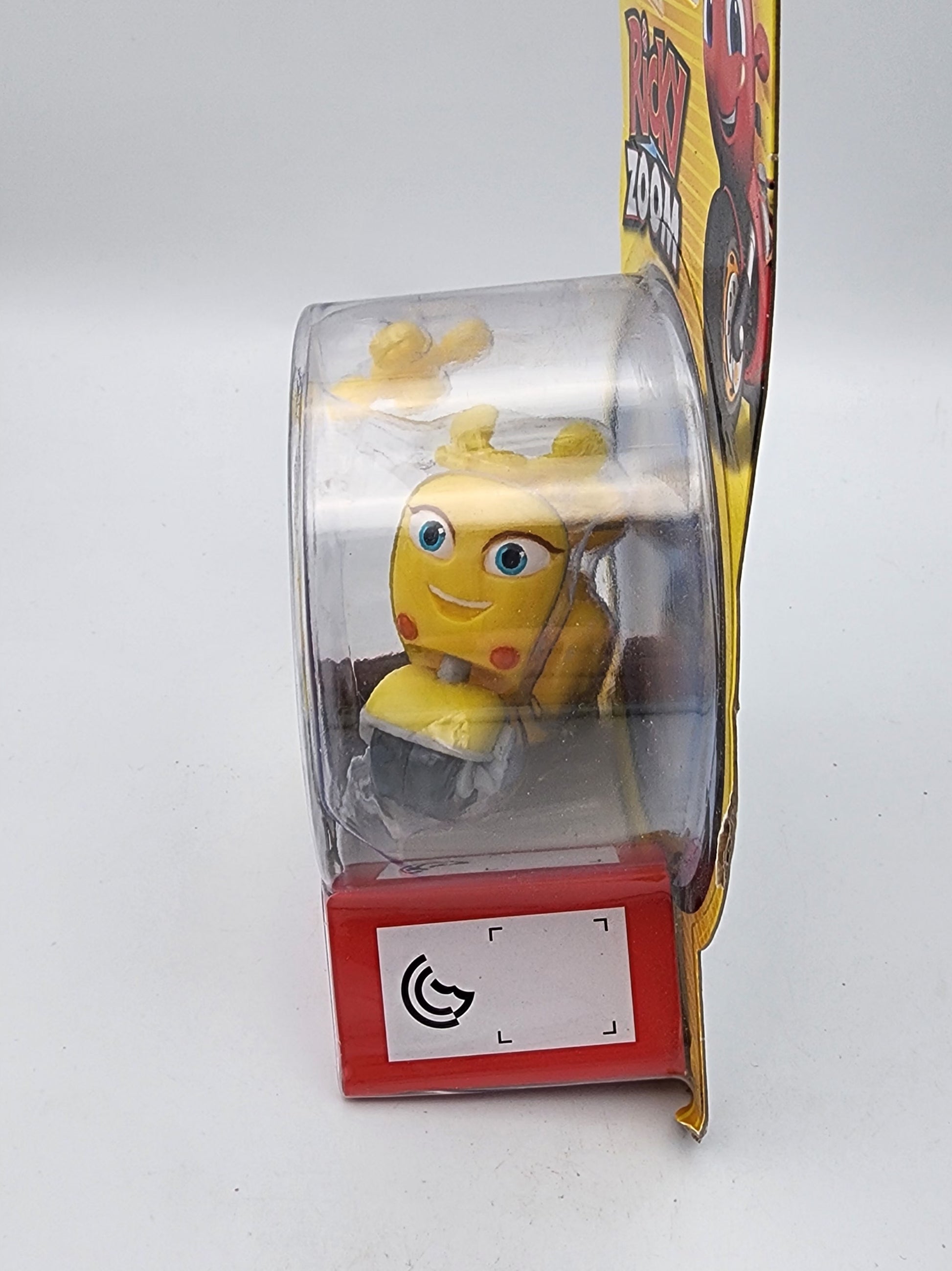 Yellow toy figure in a transparent display case with a red base on a white background