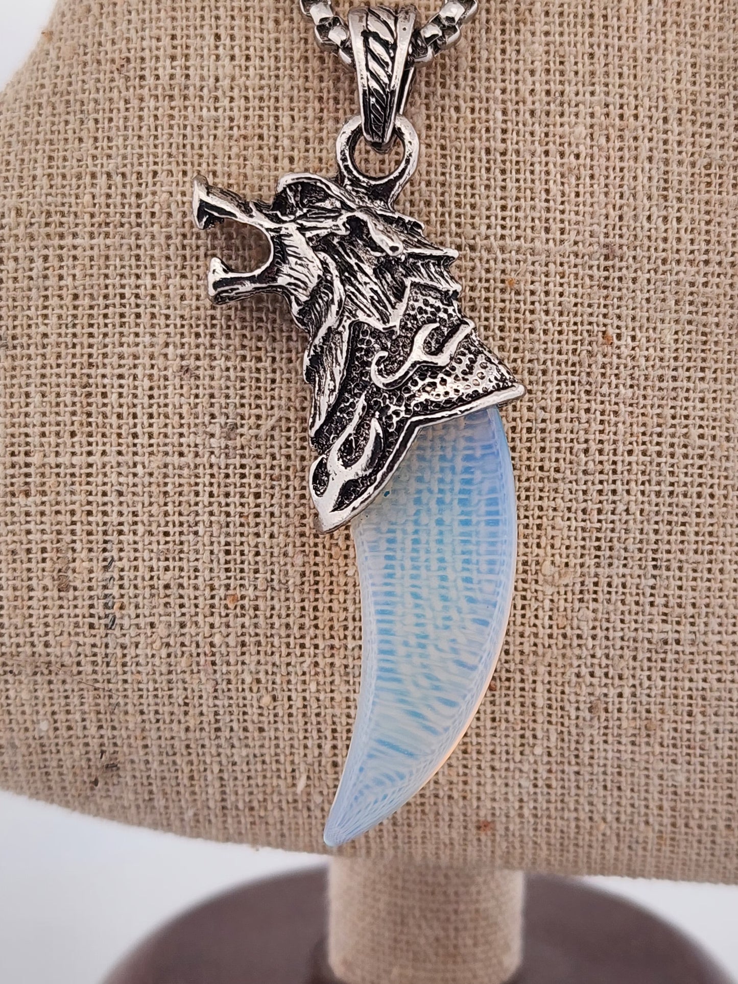 Silver pendant with a blue tooth on a beige fabric background