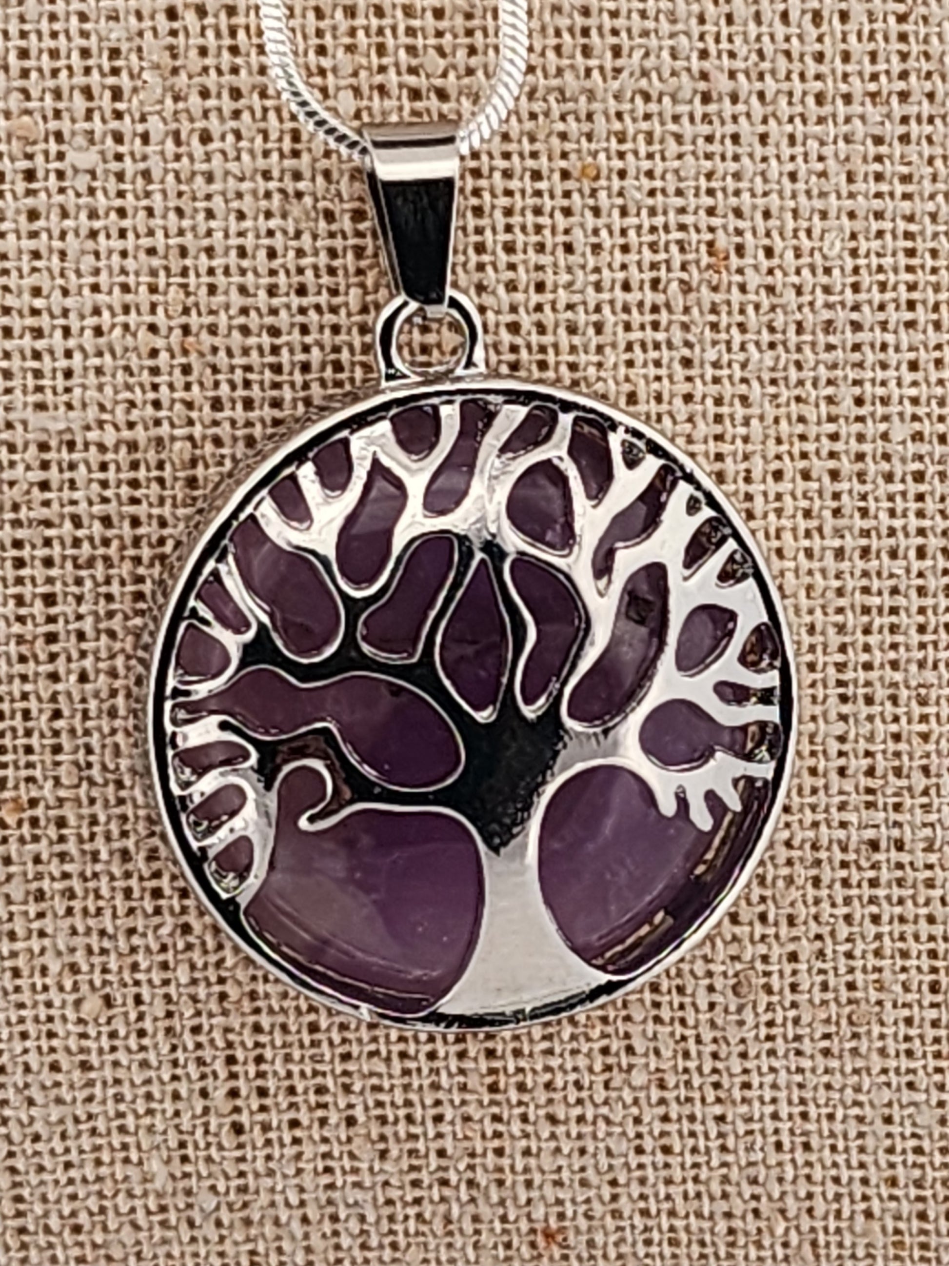 Tree of life pendant with purple design on a beige fabric background