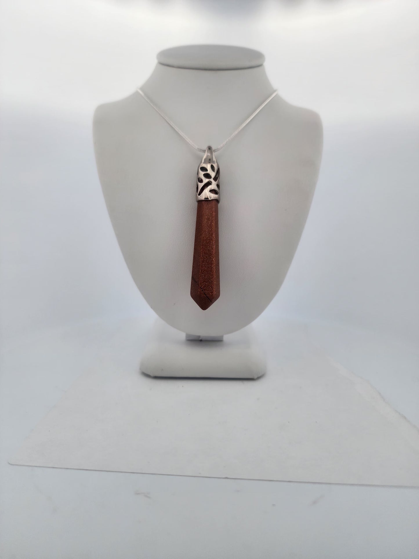 Necklace with a wooden pendant on a mannequin bust against a white background