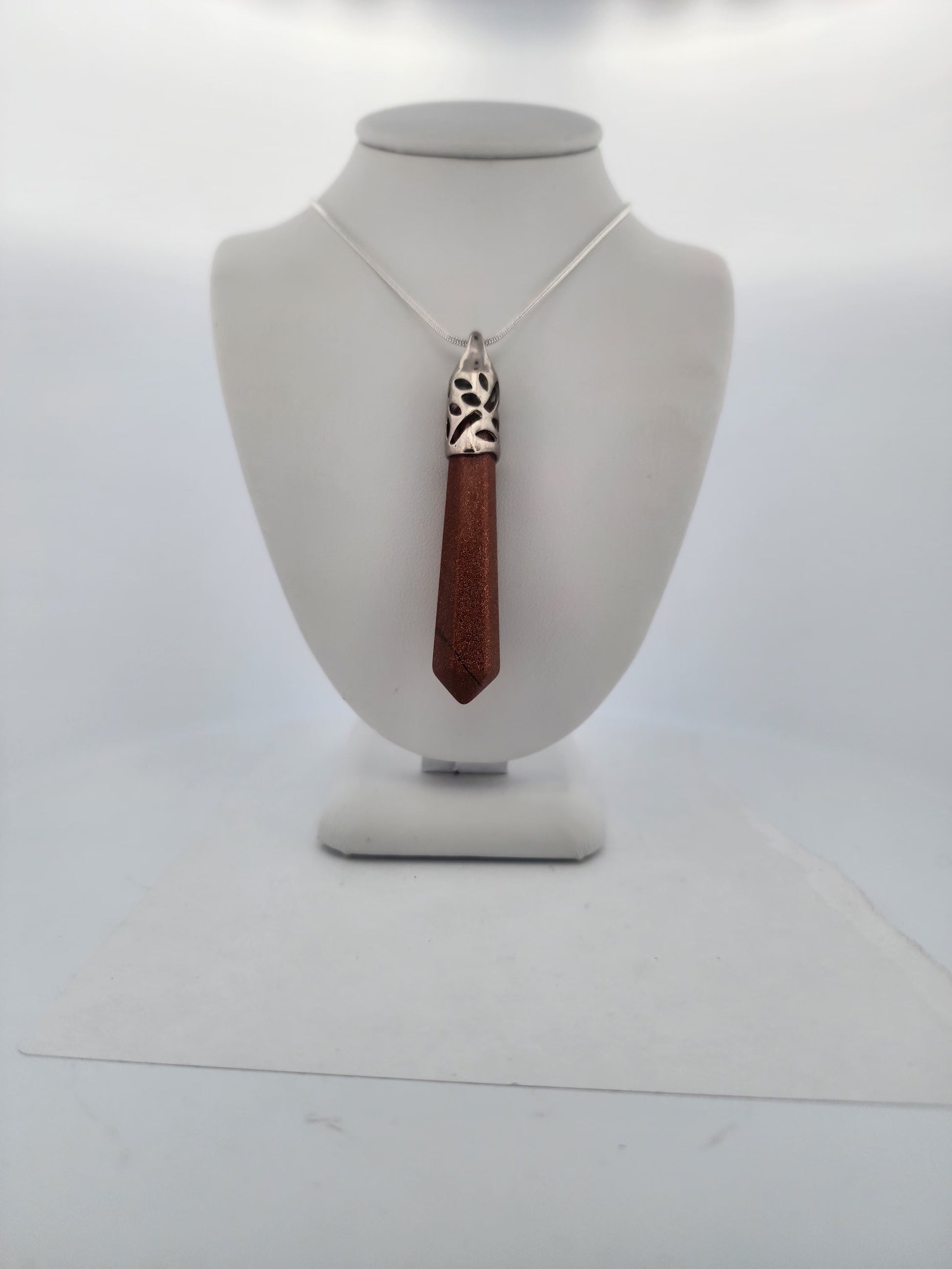 Necklace with a wooden pendant on a mannequin bust against a white background
