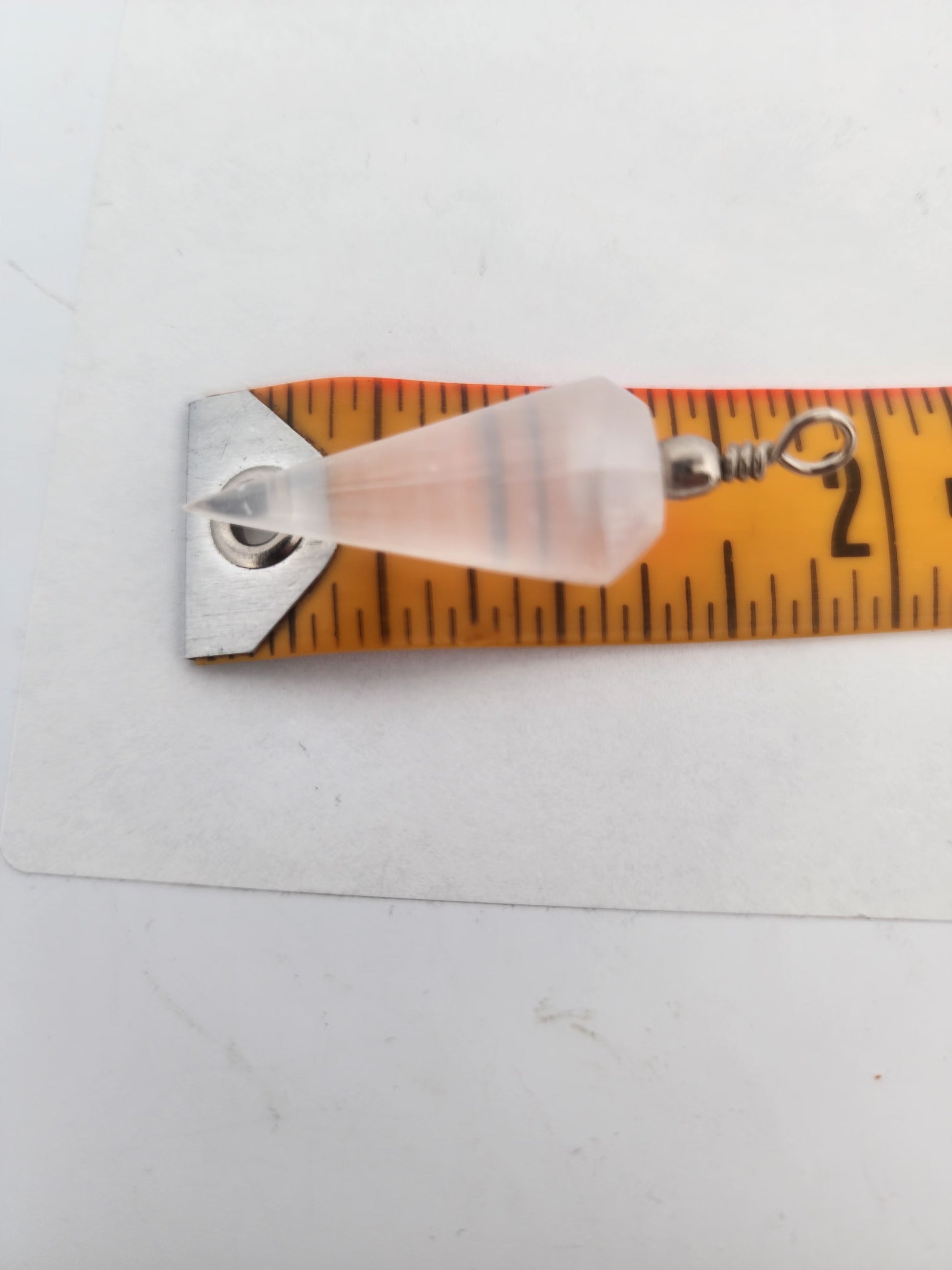 Pearl earring on a ruler for size measurement against a white background