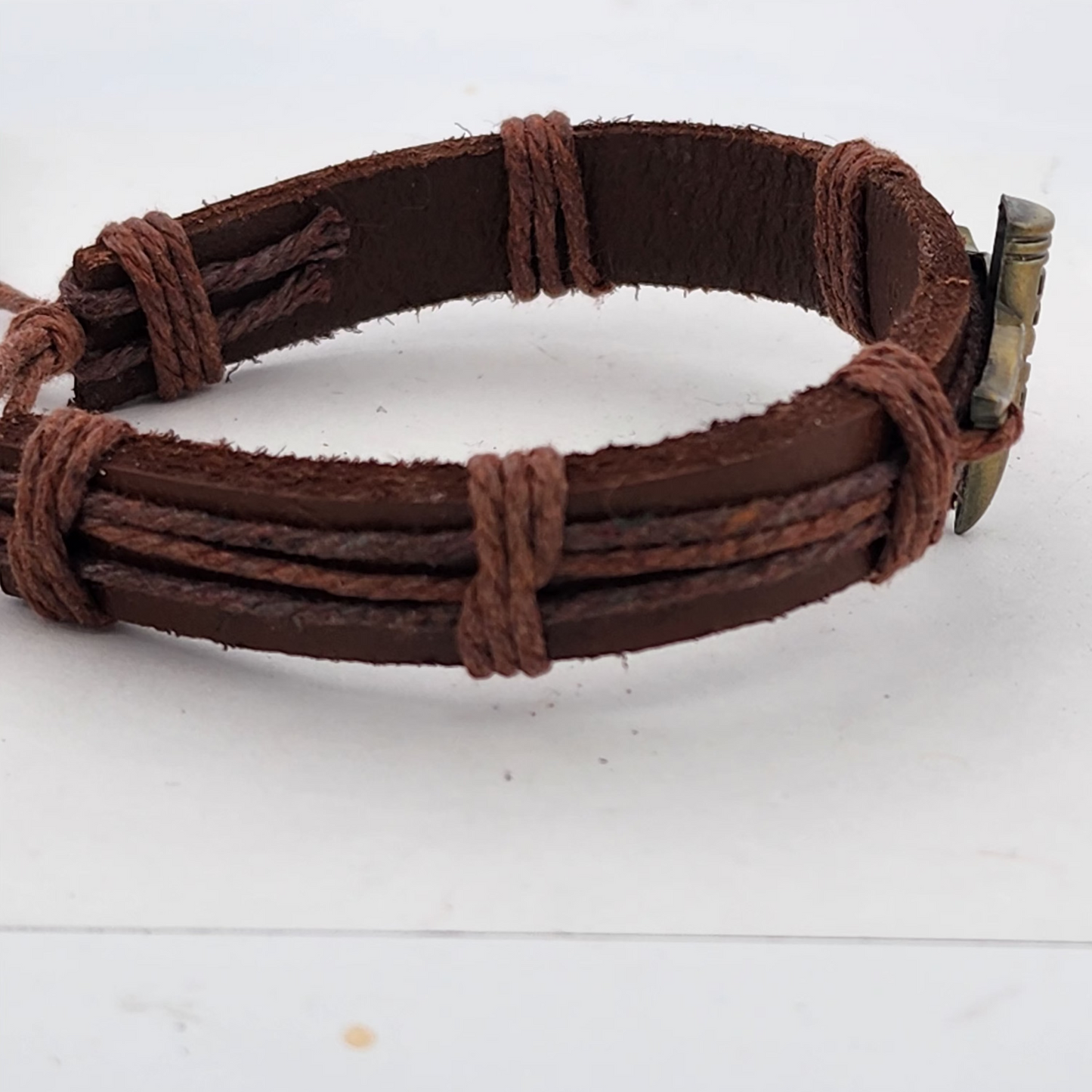 Brown leather bracelet with a metal clasp on a white background