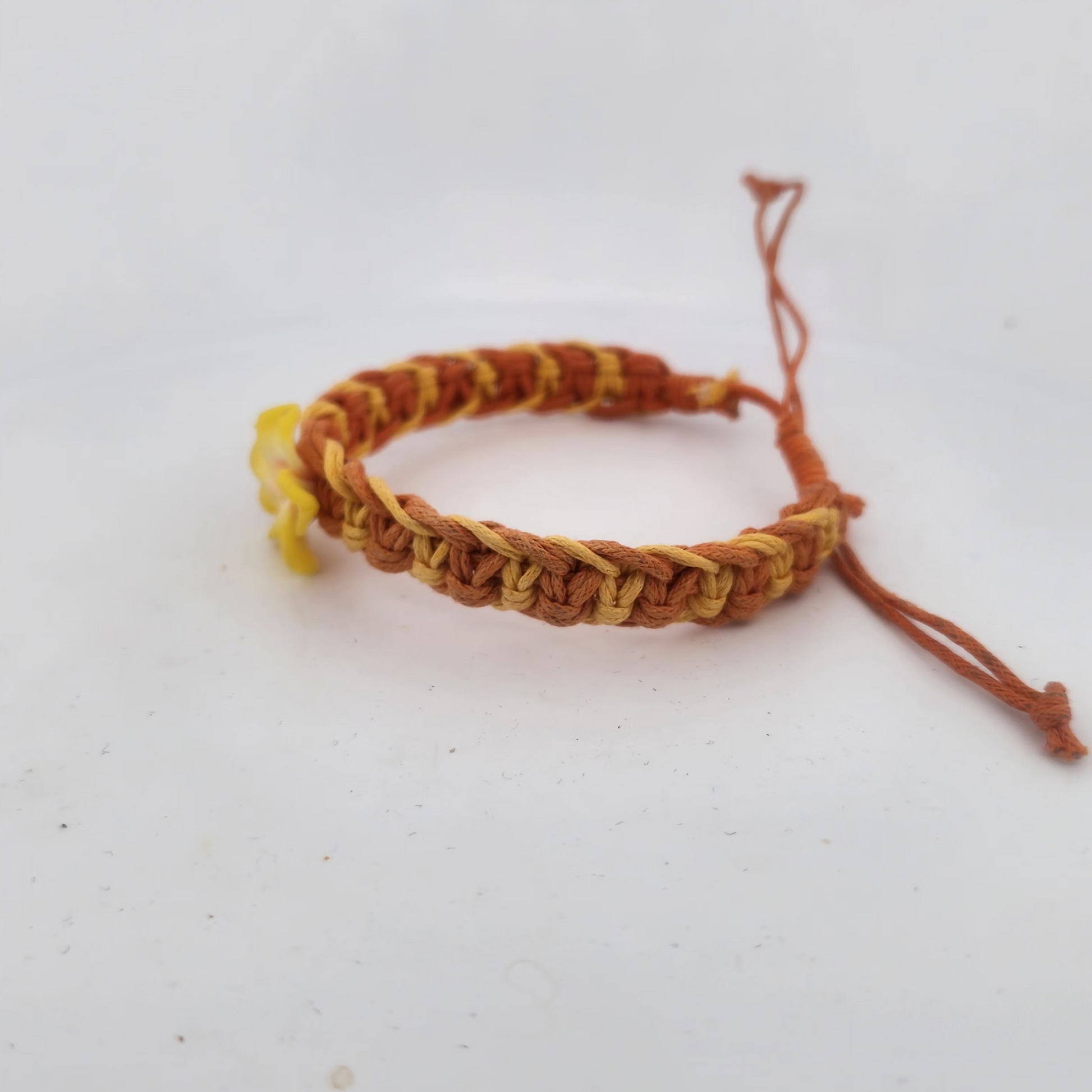 Bracelet with braided design in orange and yellow on a white background