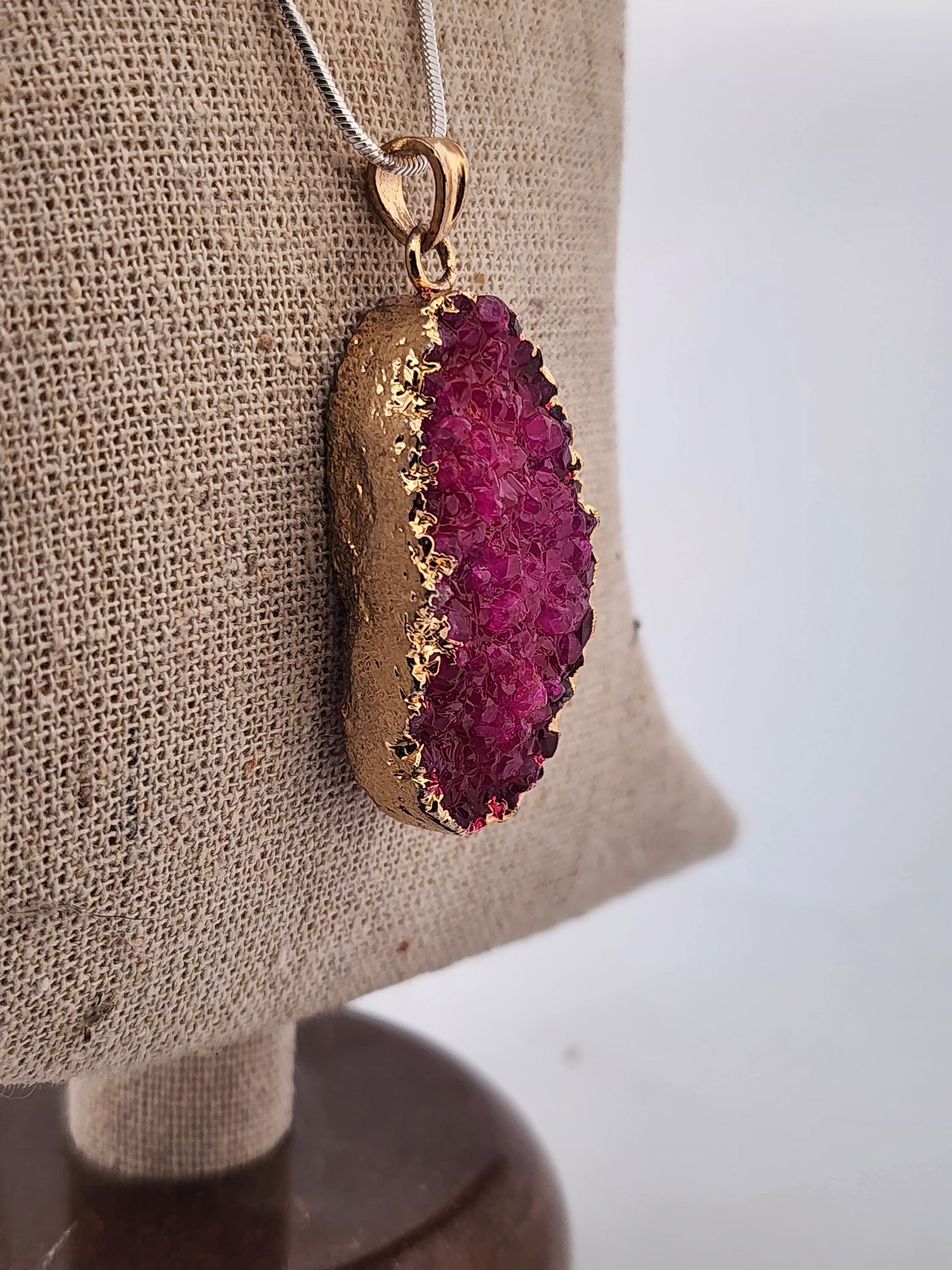 Gold and purple pendant on a mannequin bust with a neutral background