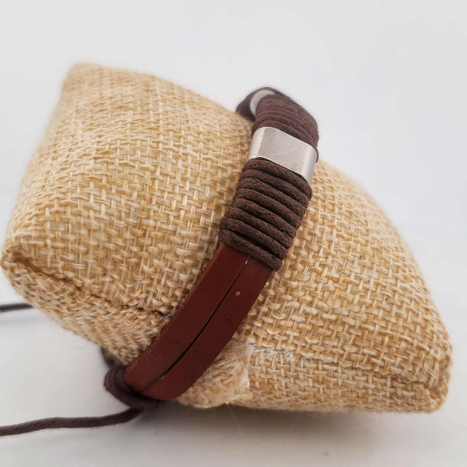 Brown braided bracelet on a textured beige surface