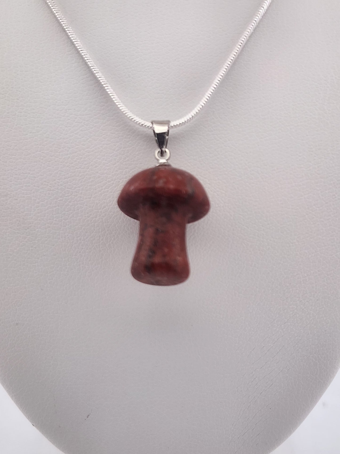 Red mushroom-shaped pendant on a silver chain against a gray background