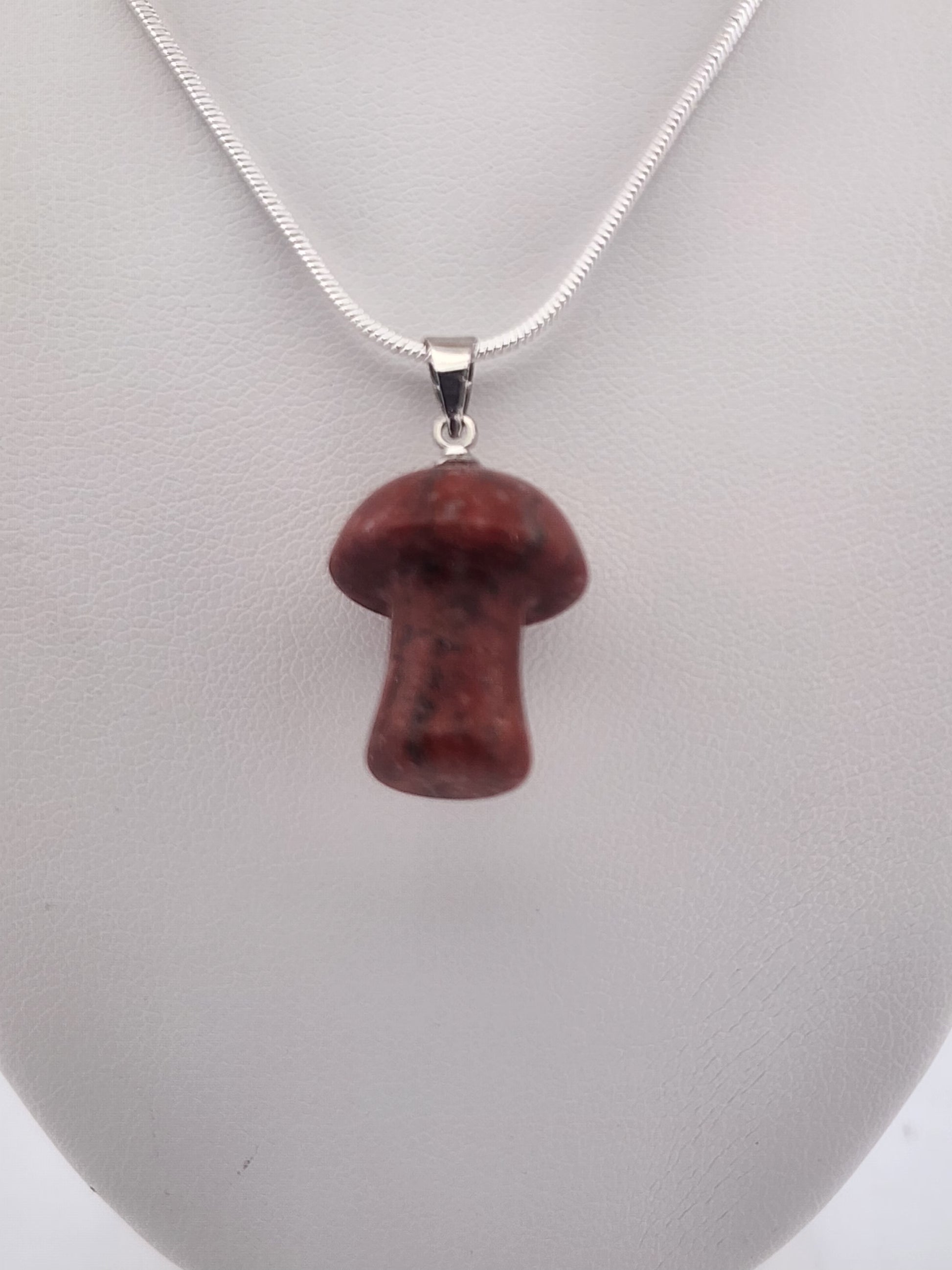 Red mushroom-shaped pendant on a silver chain against a gray background