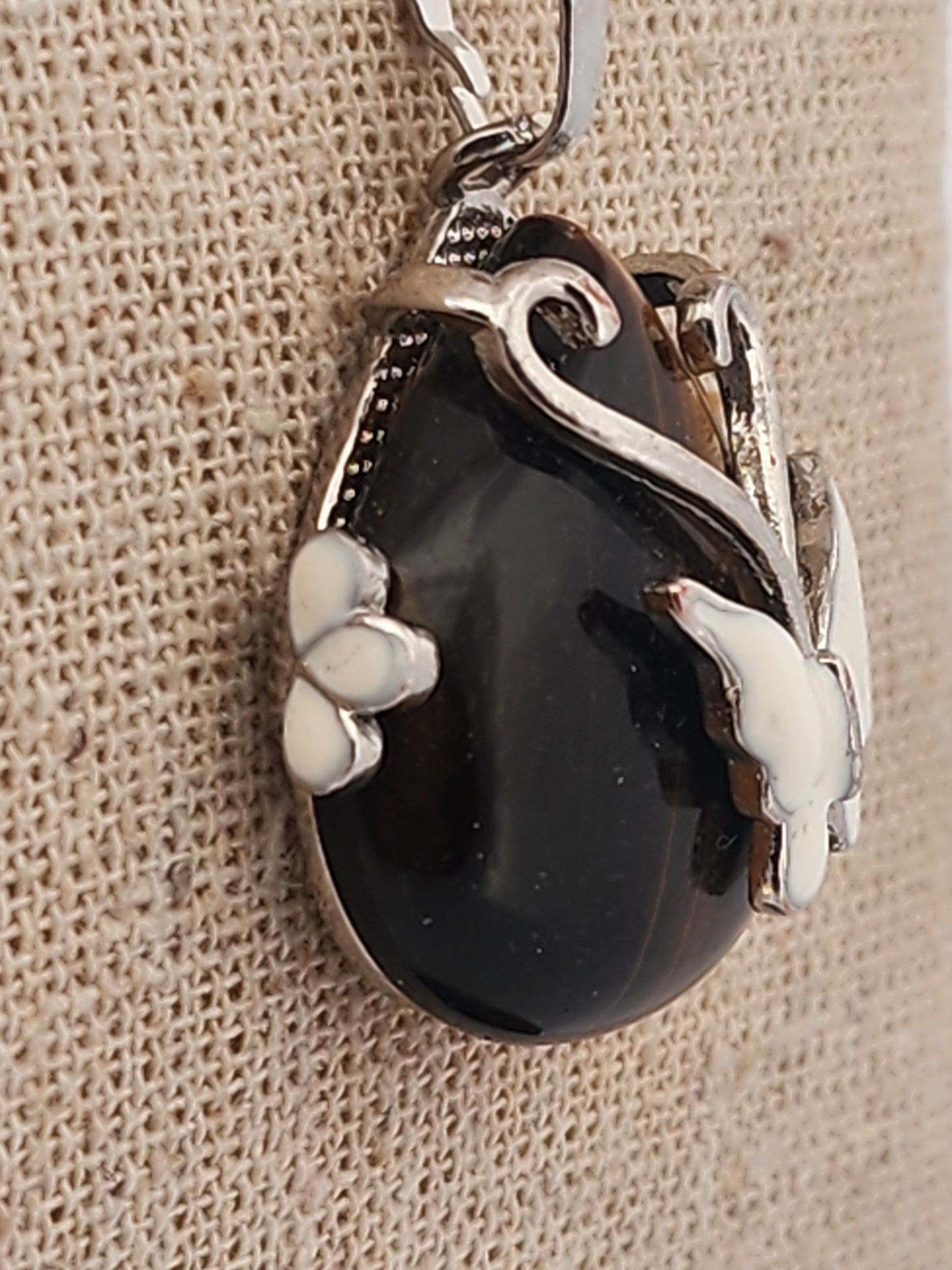 Silver pendant with a black stone on a beige fabric background