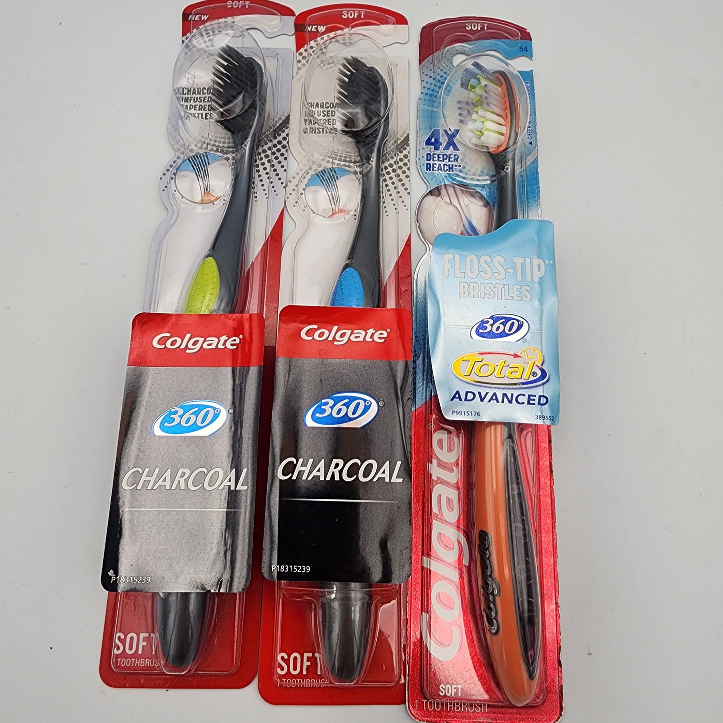 Three Colgate toothbrushes in packaging on a gray background