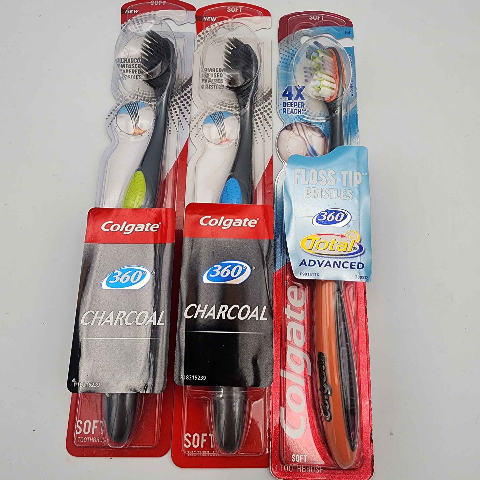 Three Colgate toothbrushes in packaging on a gray background