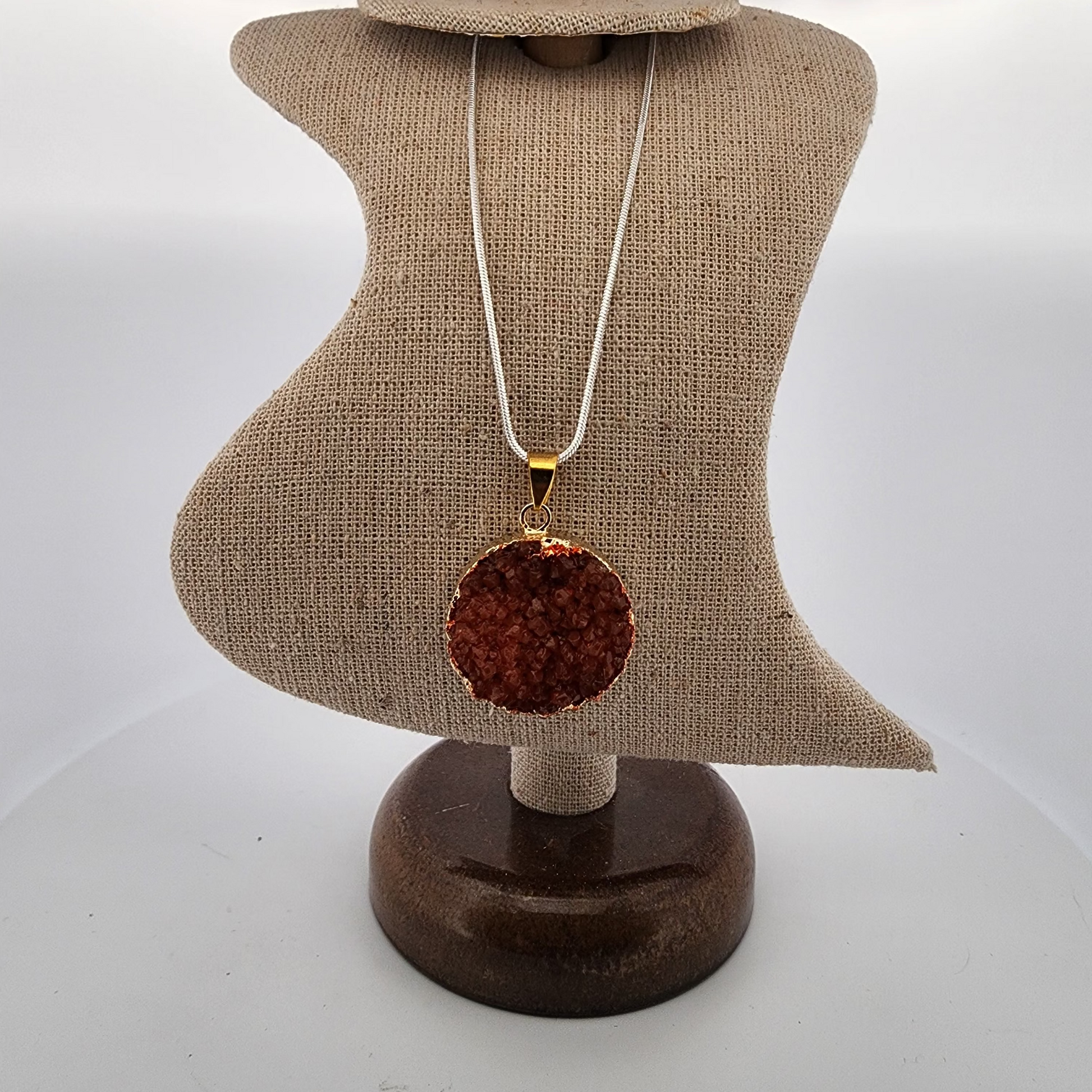 Necklace with a round, brown pendant on a mannequin bust against a white background