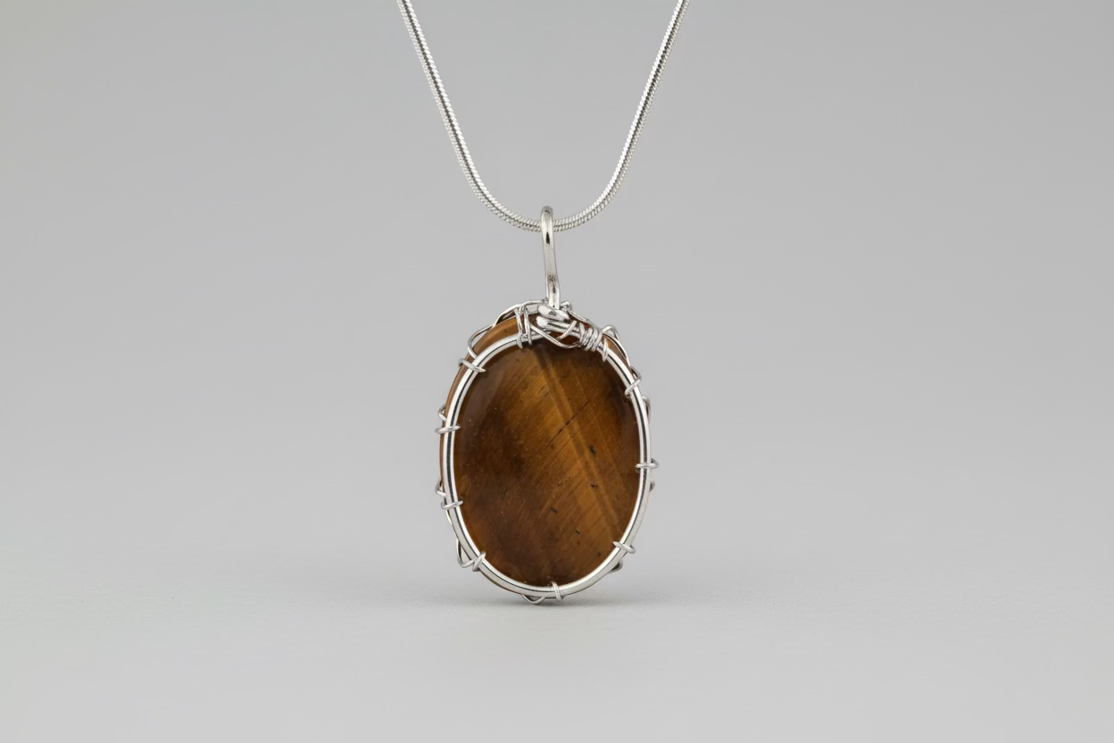 Tiger's eye pendant with silver wire wrapping on a beige fabric background