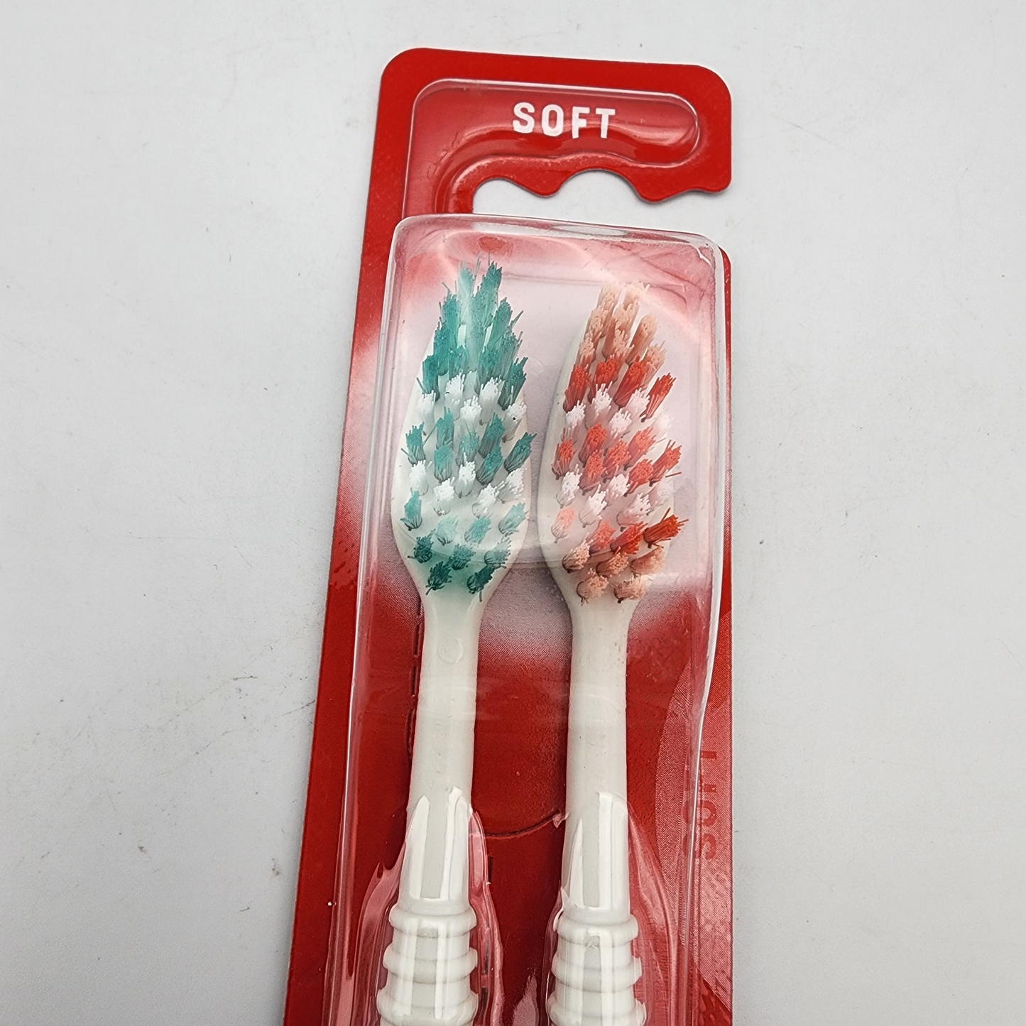 Two soft bristle toothbrushes on a red card with 'SOFT' text against a white background.