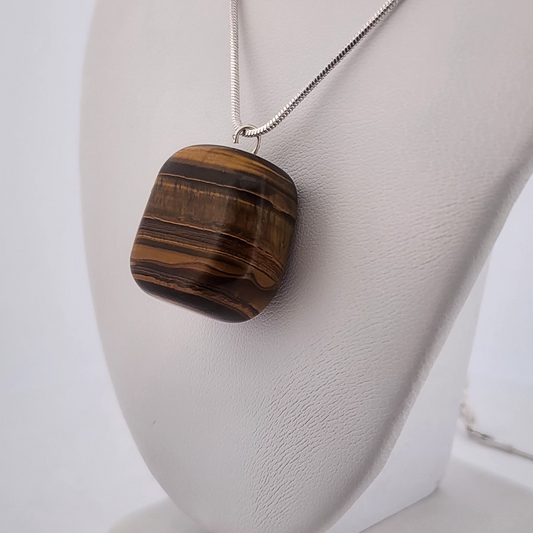 Tiger eye pendant necklace on a white stand with a plain background