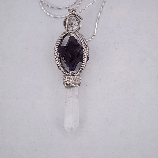Necklace with a pendant featuring a dark purple gemstone and white crystal on a light gray background